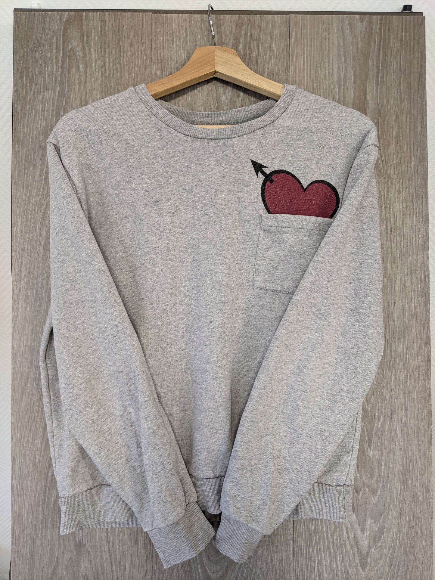 Angled front view of grey sweater with heart design
