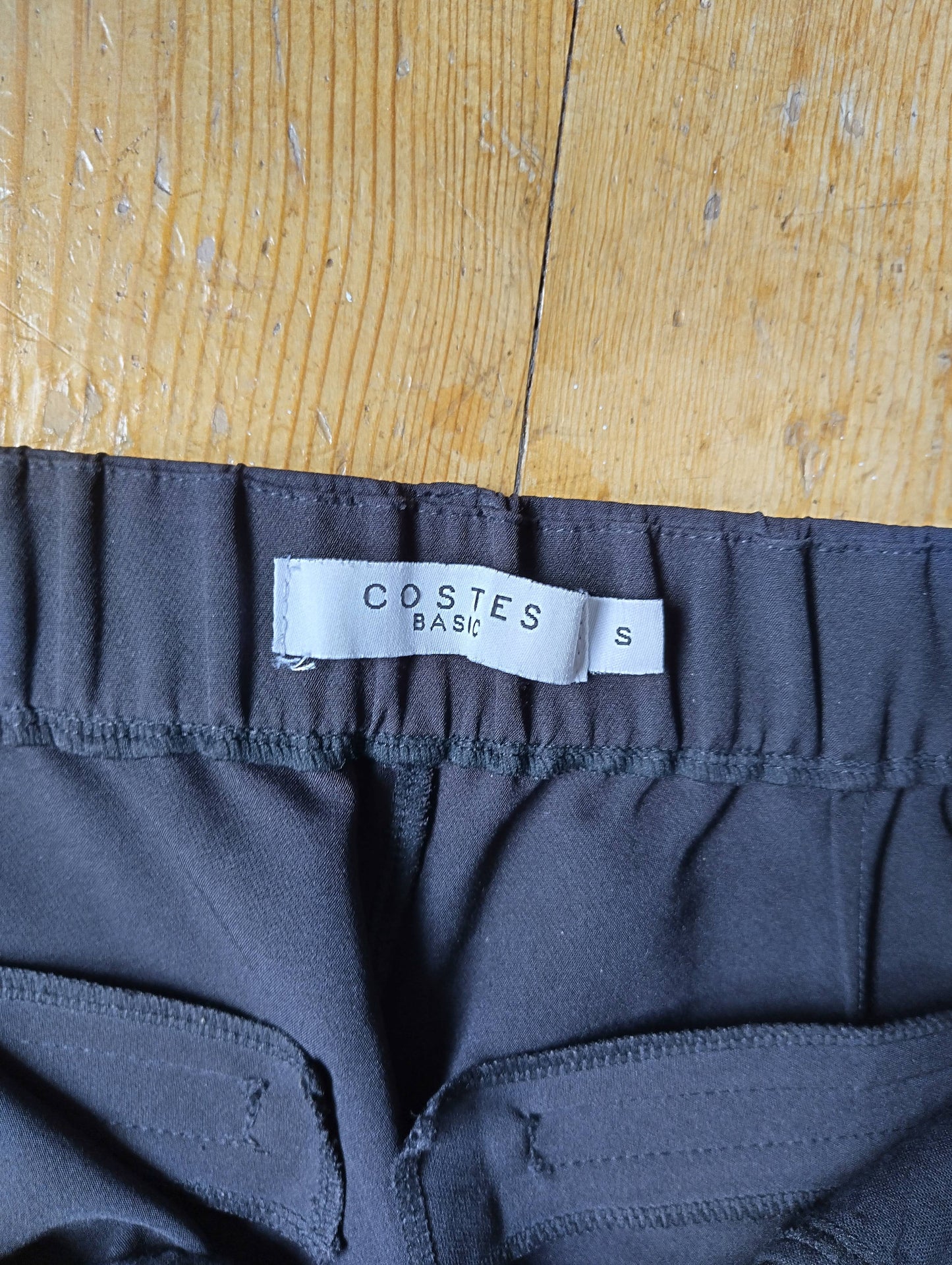 Close-up of Costes label on black chinos