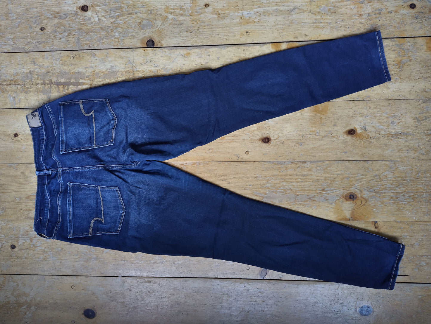Back side view of dark blue jeans on wooden floor