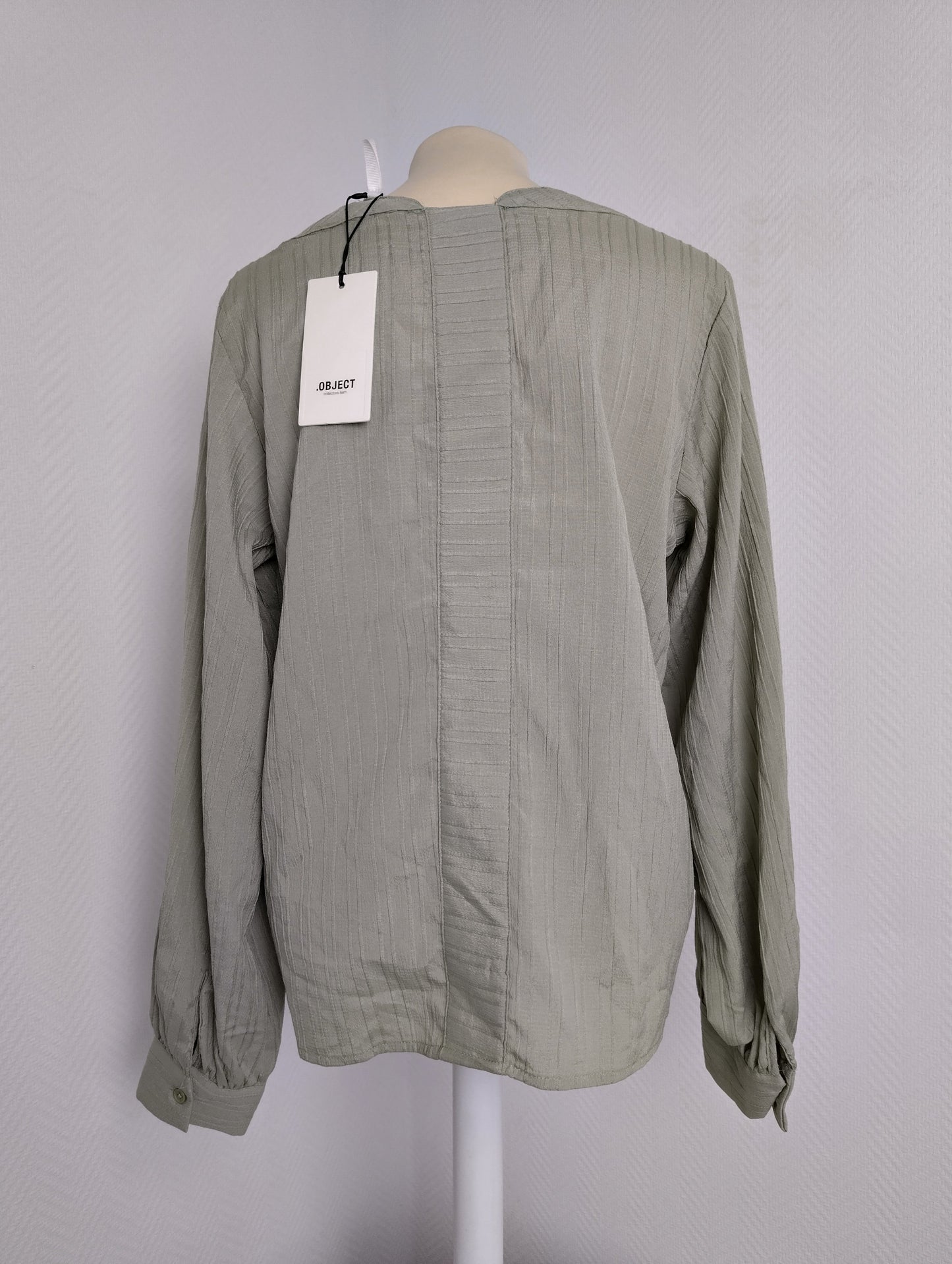 Back view of green long-sleeve blouse with tag