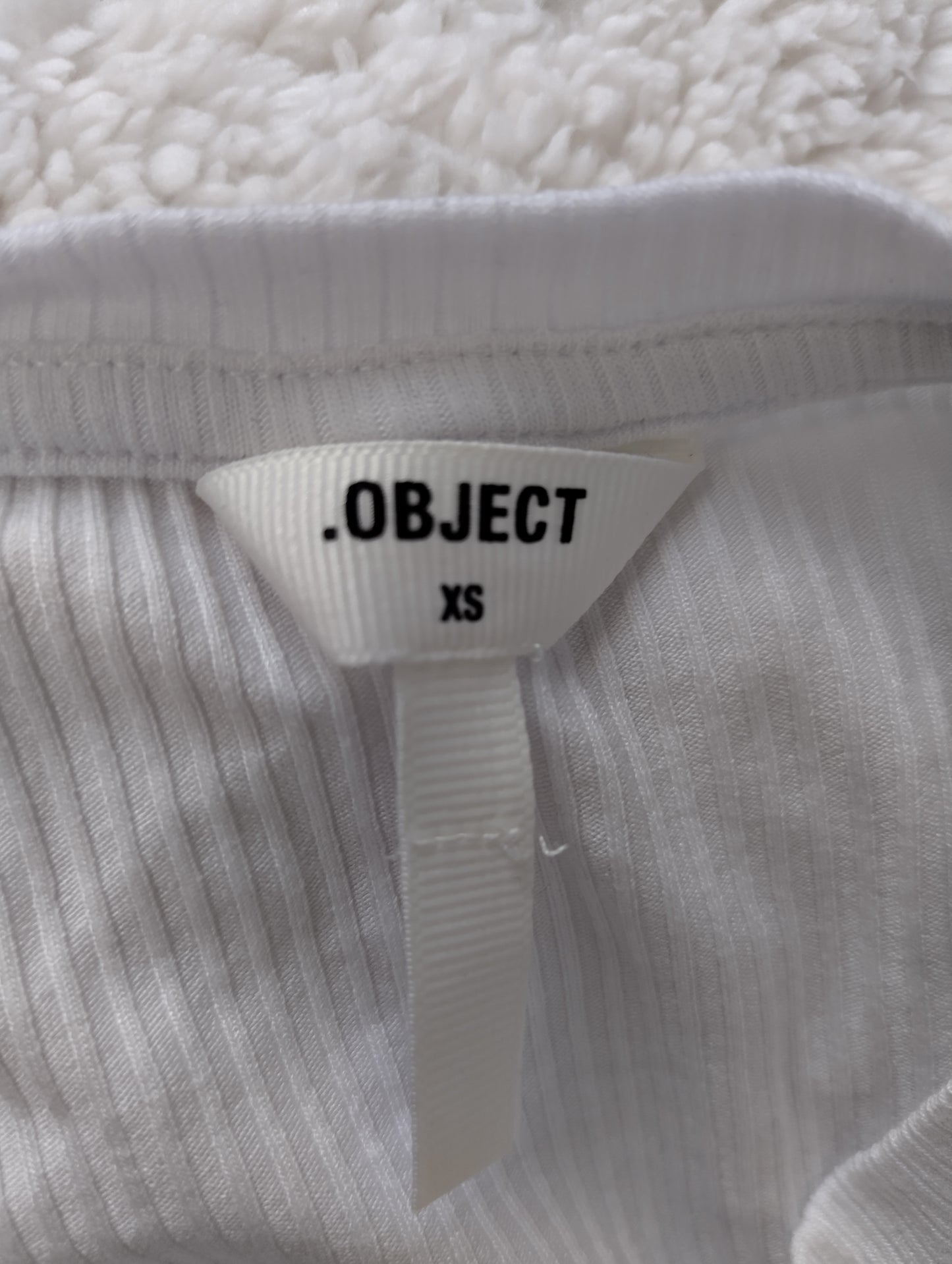 Label showing brand and size of the white ribbed tank top