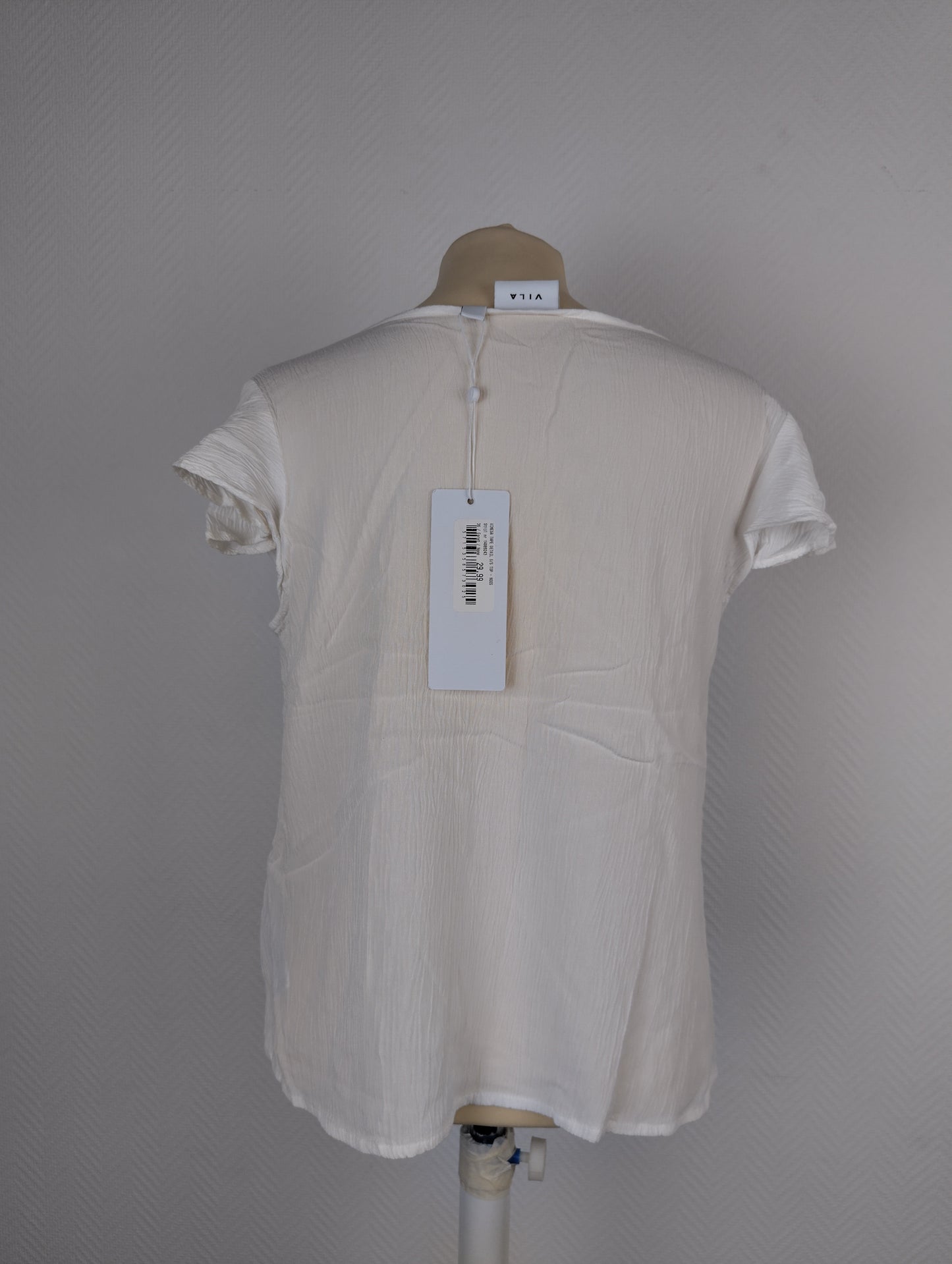 Back view of white textured blouse with tag