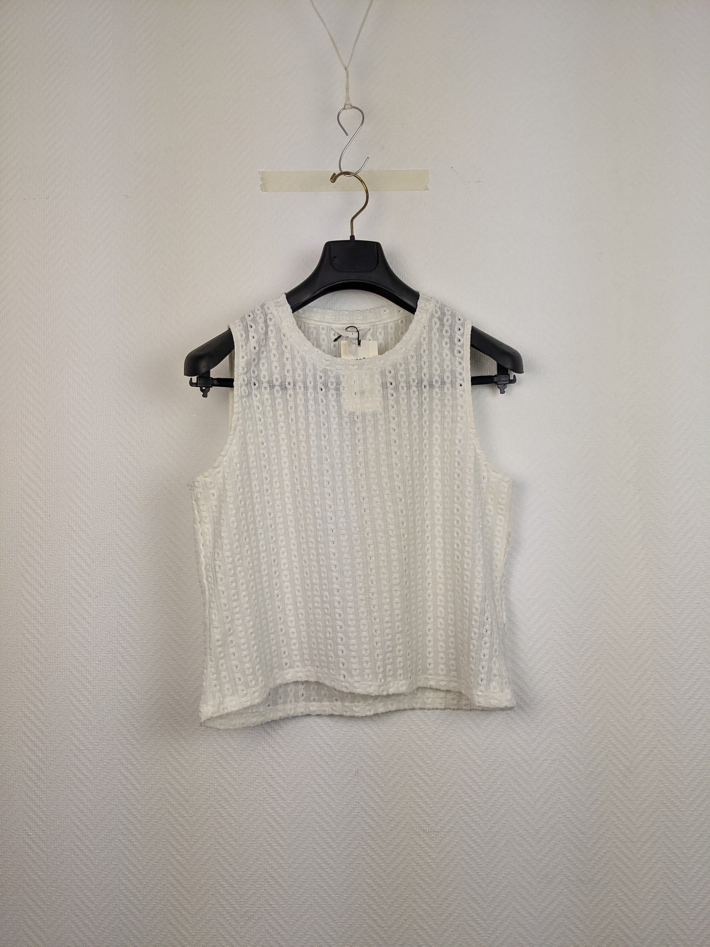 Front view of white eyelet sleeveless top on hanger