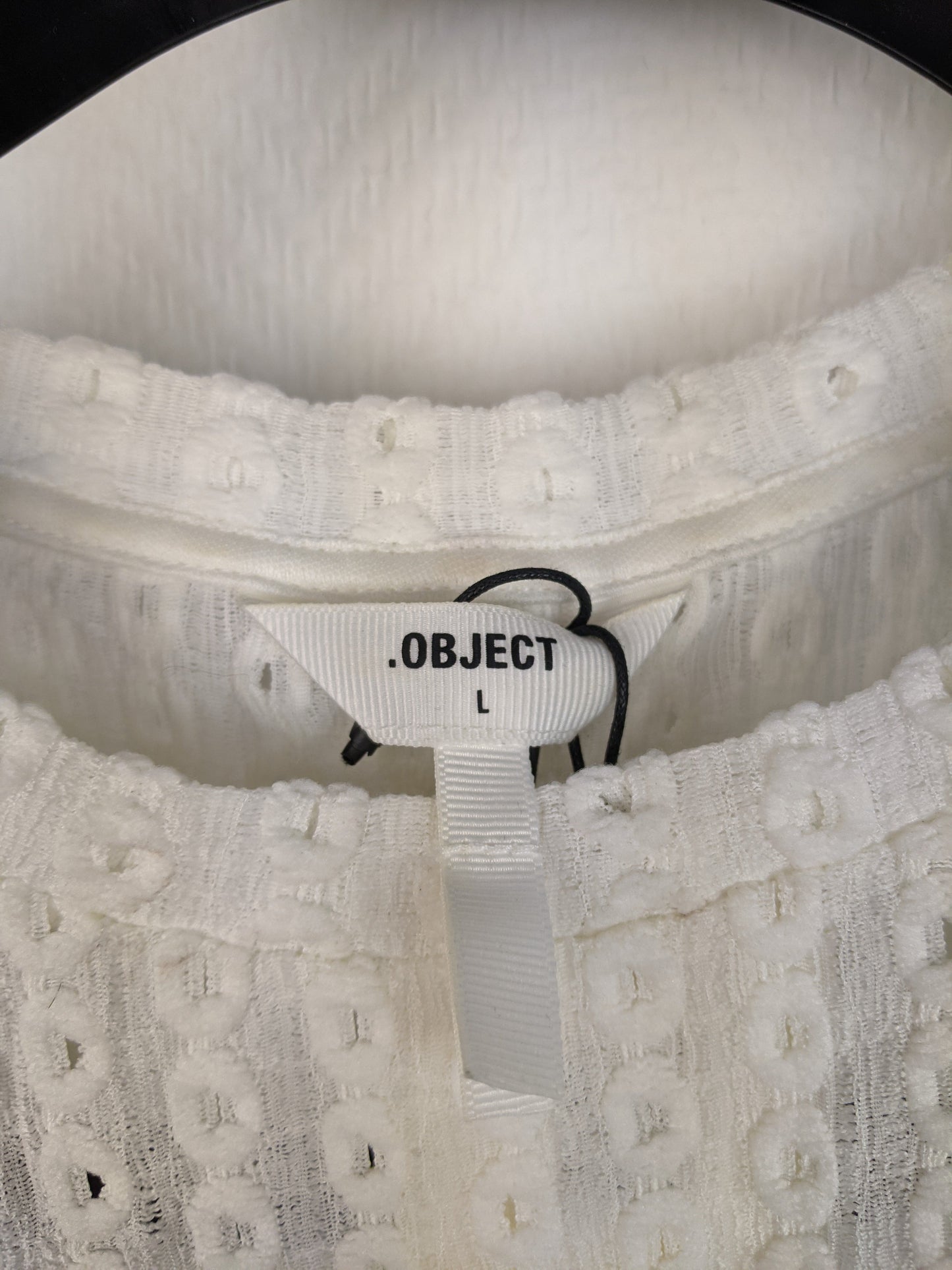 Close-up of label on white eyelet sleeveless top