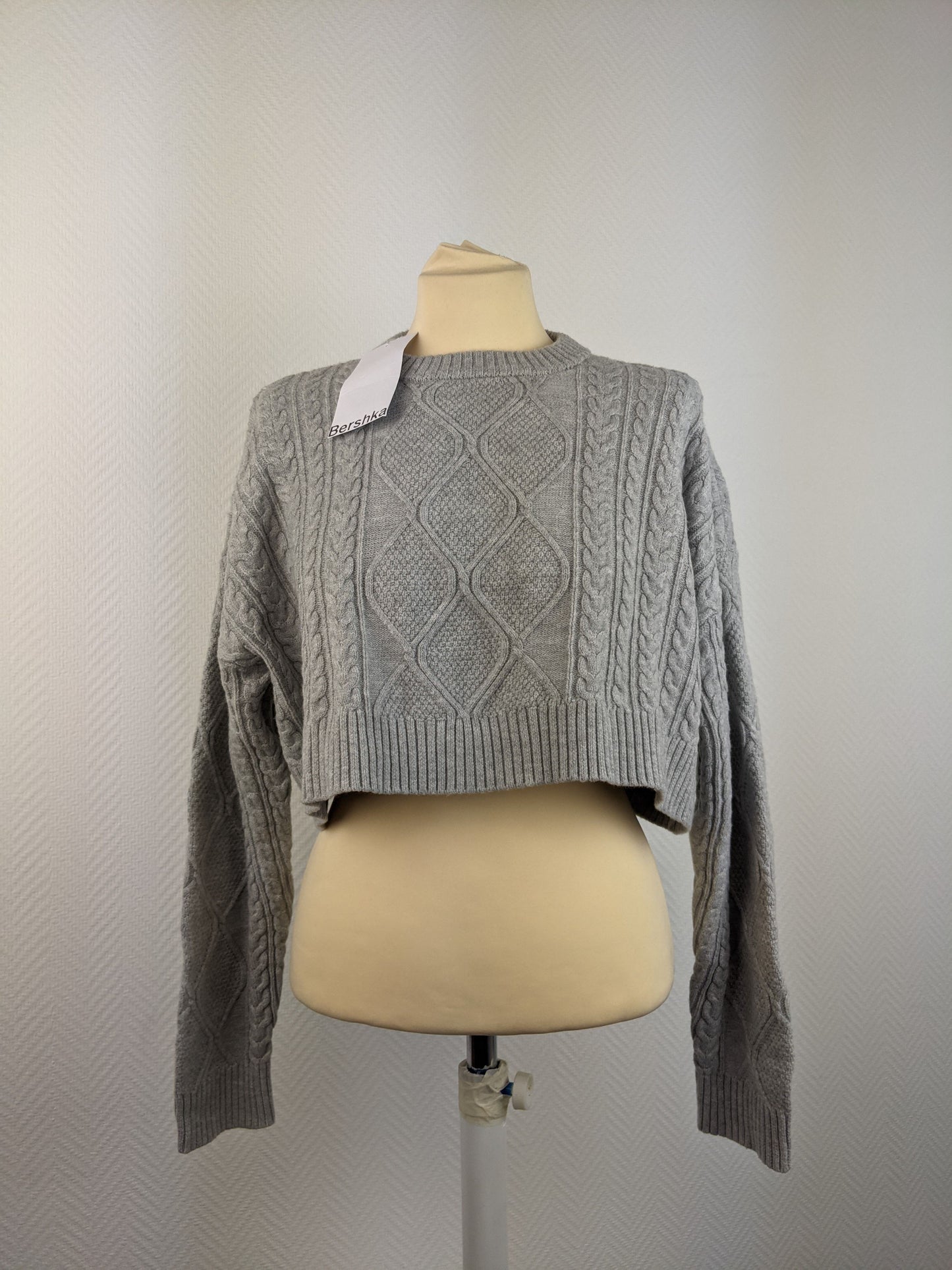 Front view of grey cable knit sweater on mannequin