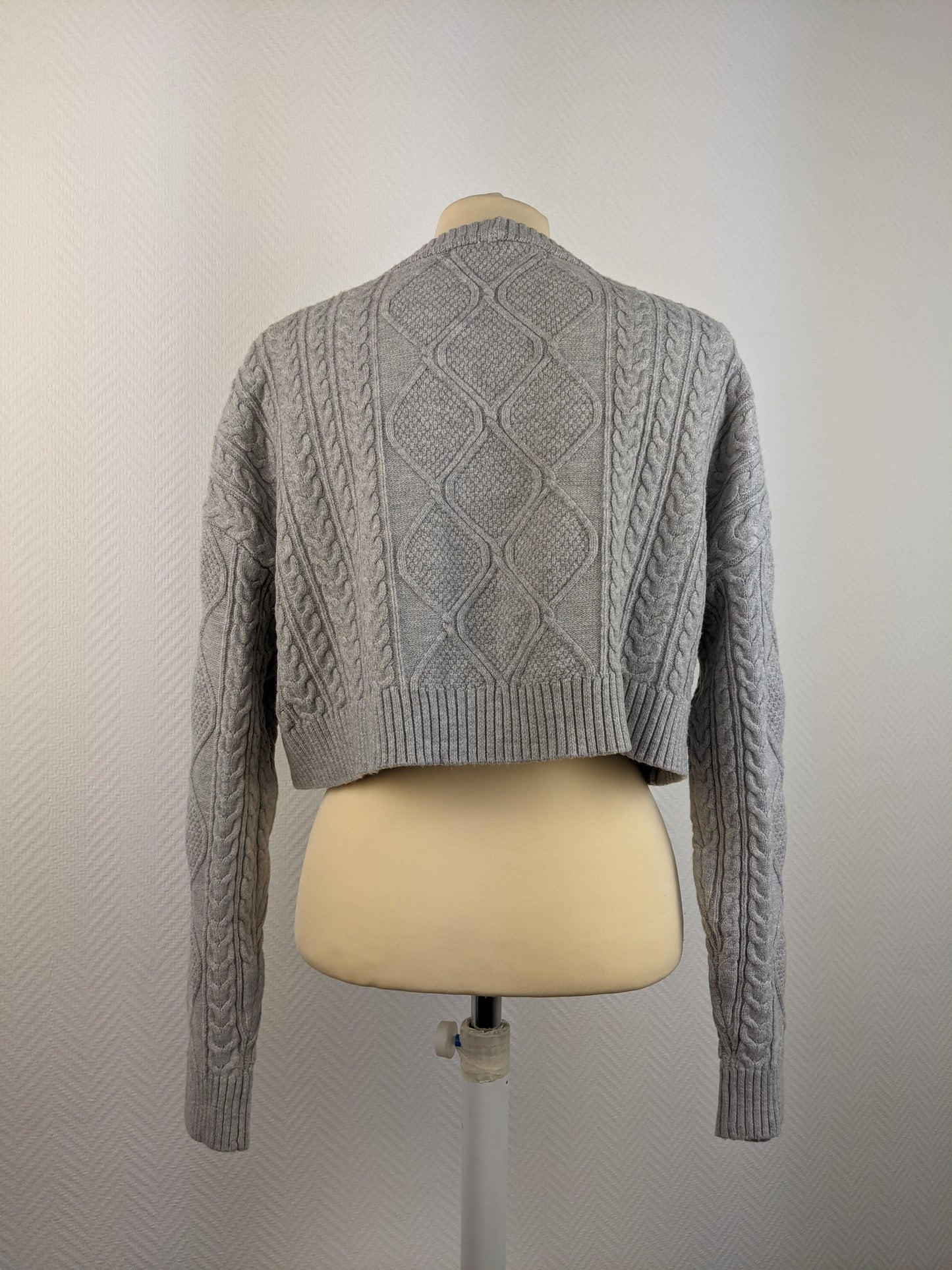 Back view of grey cable knit sweater on mannequin