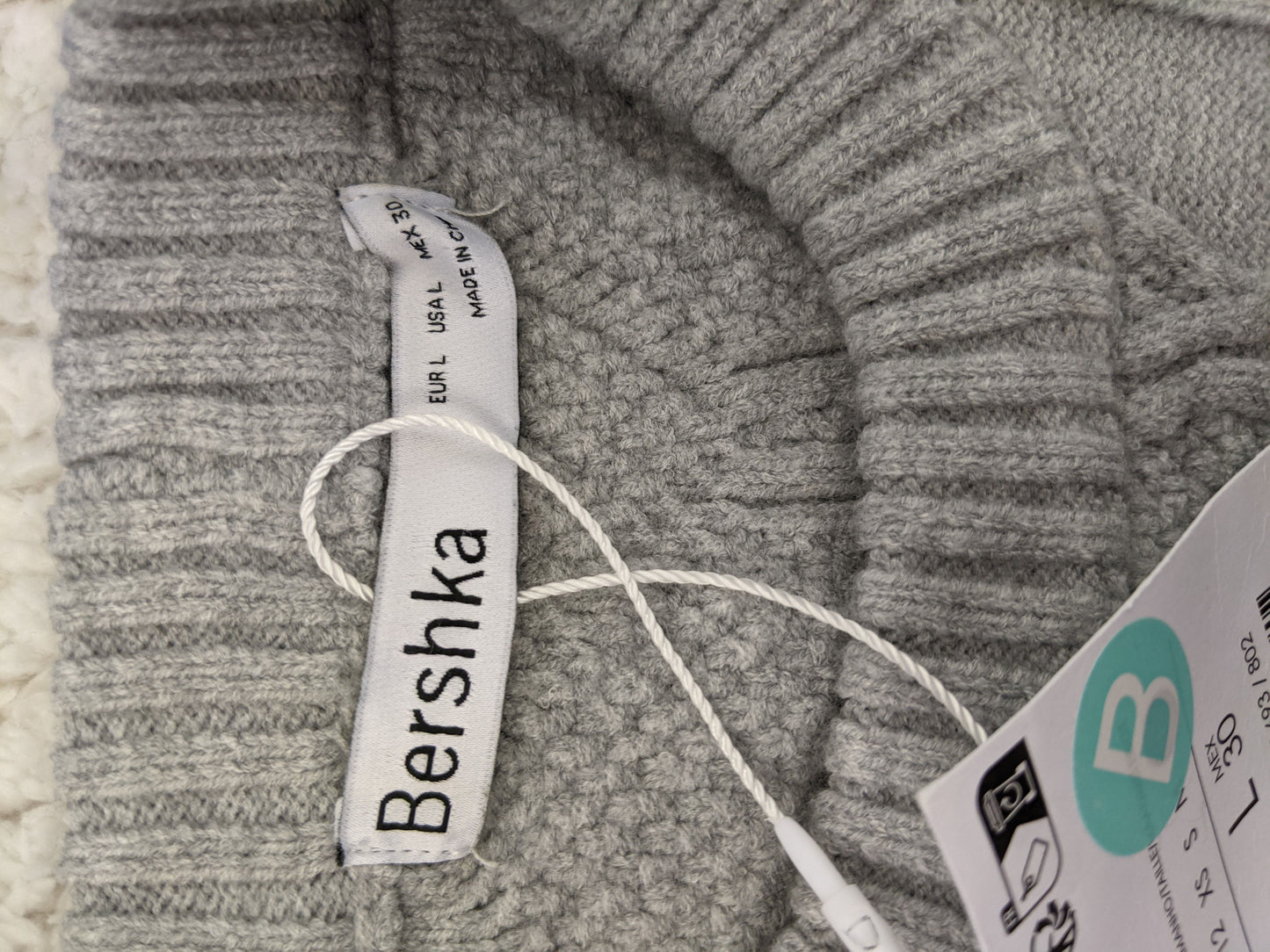 Close-up of Bershka label and tags on grey sweater
