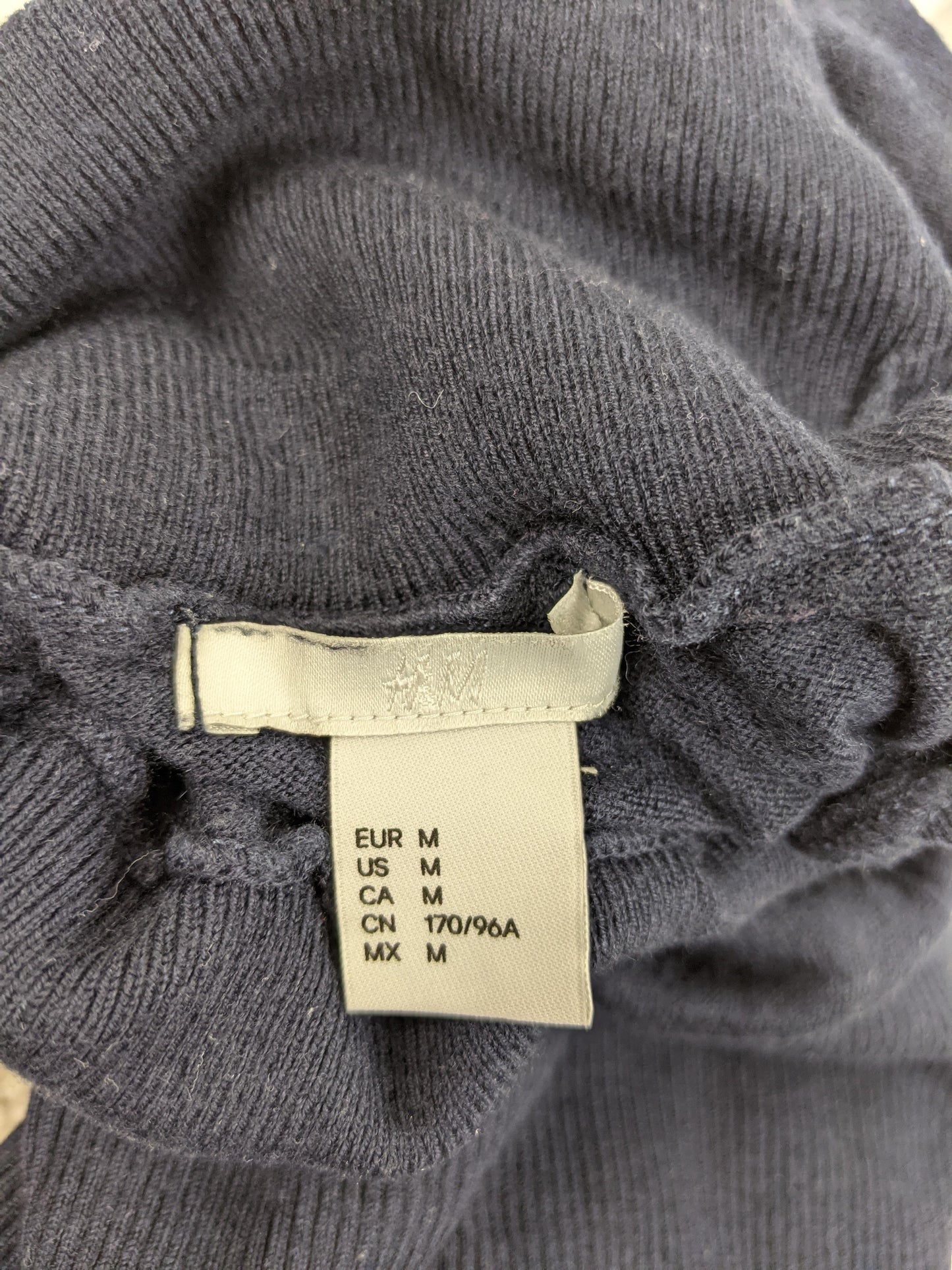 Size label of black turtleneck sweater showing size M