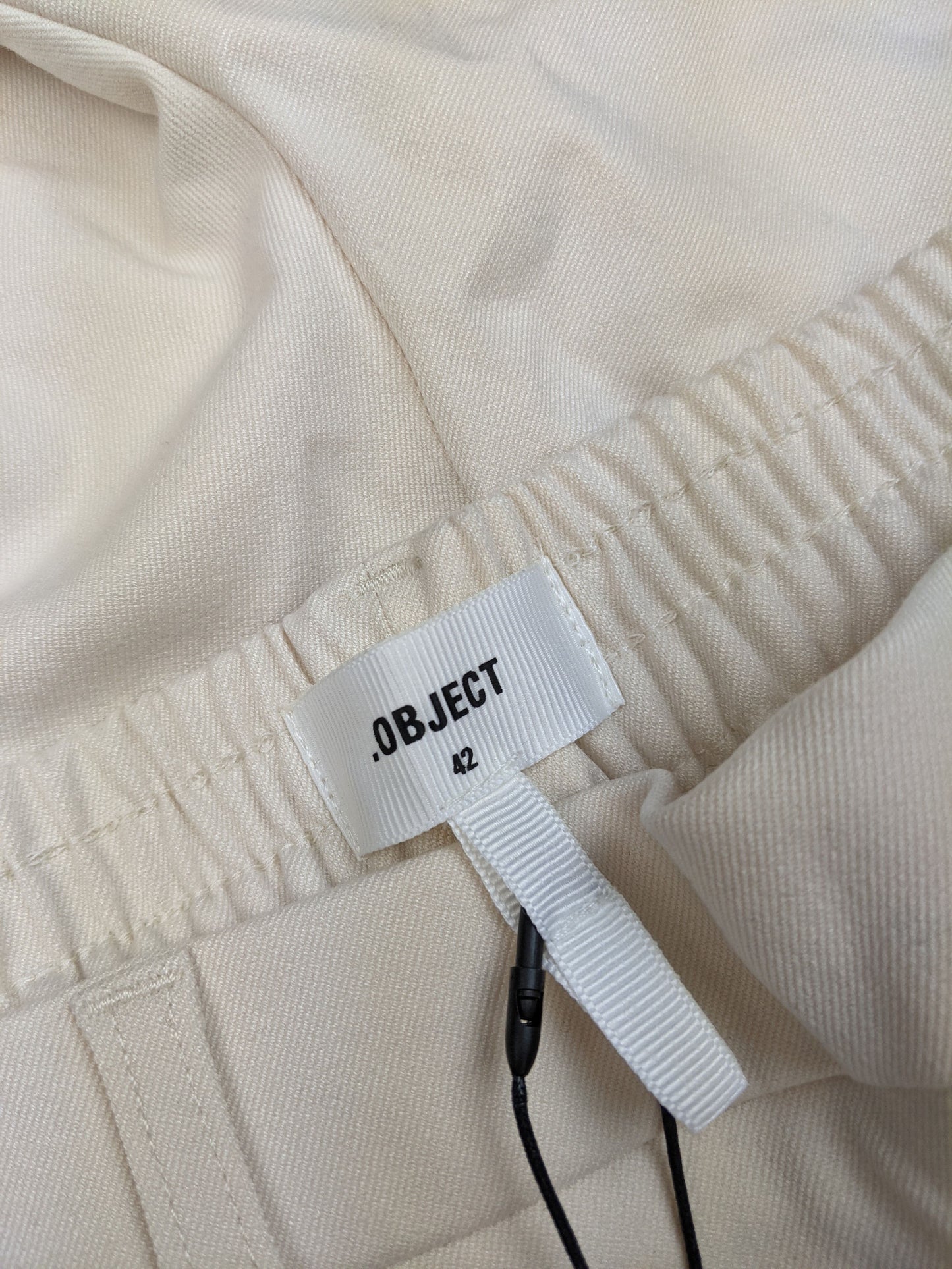 Close-up of size label on ivory wide-leg pants