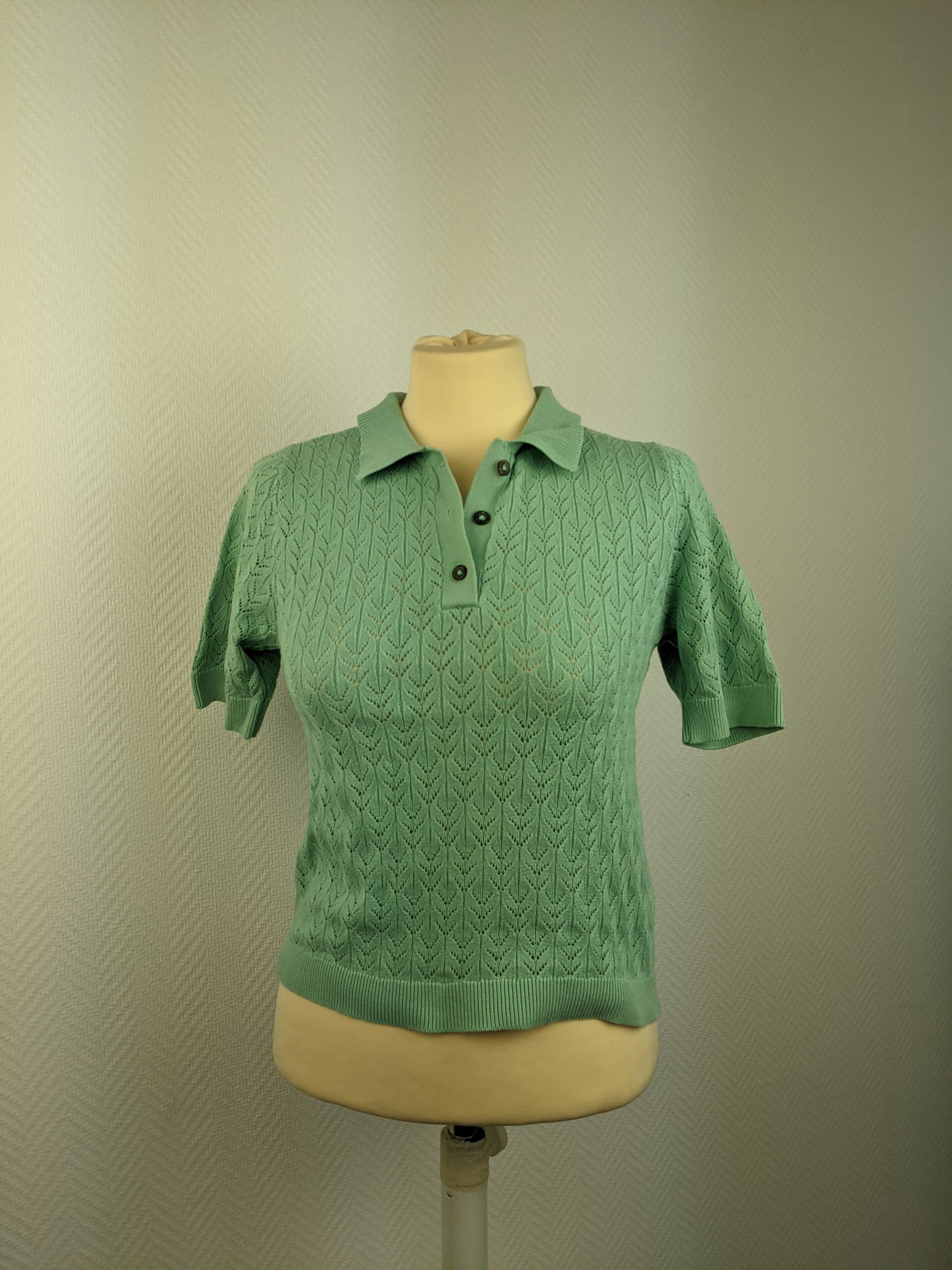 Front view of green knit polo shirt on mannequin