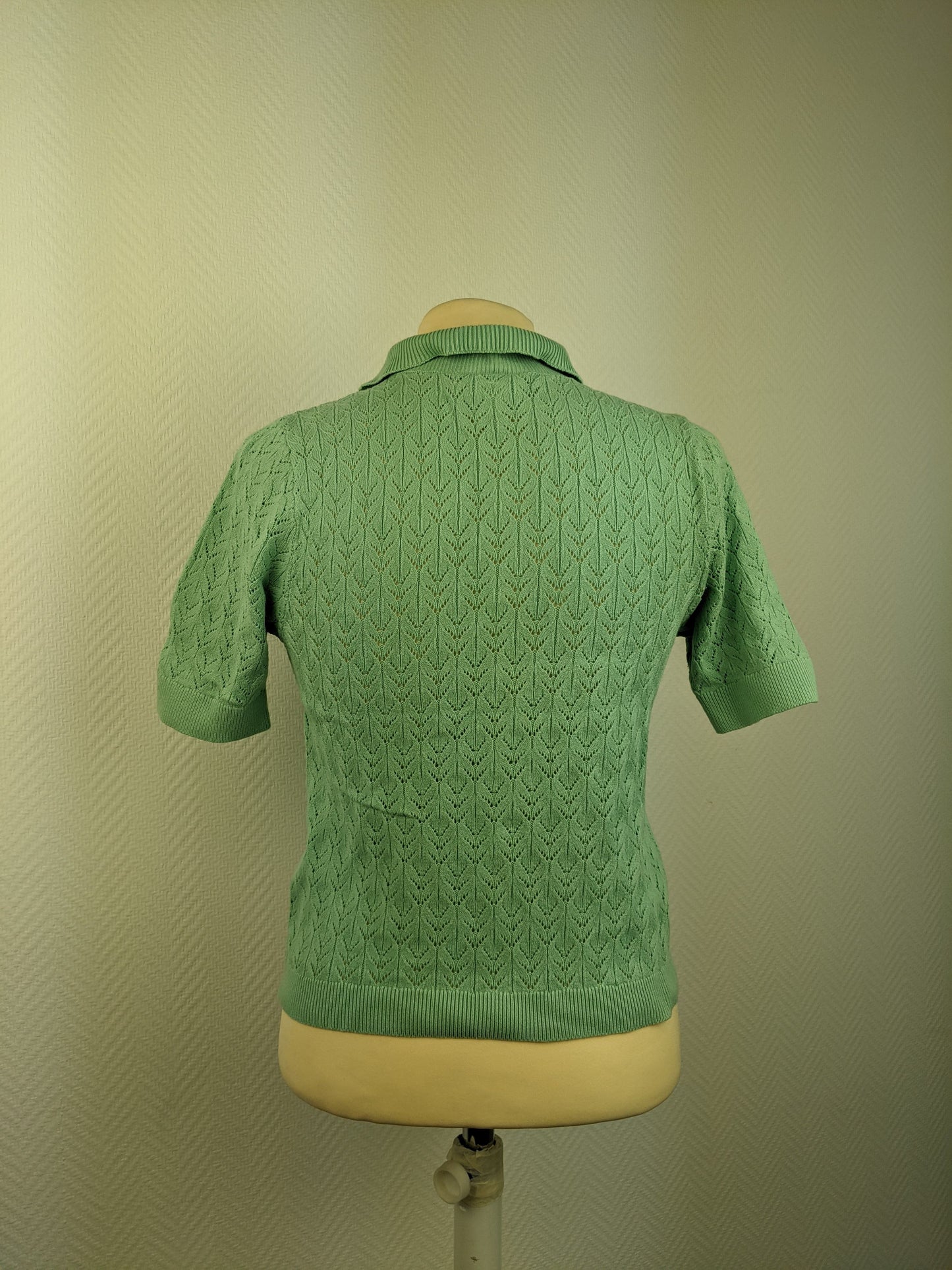 Back view of green knit polo shirt on mannequin