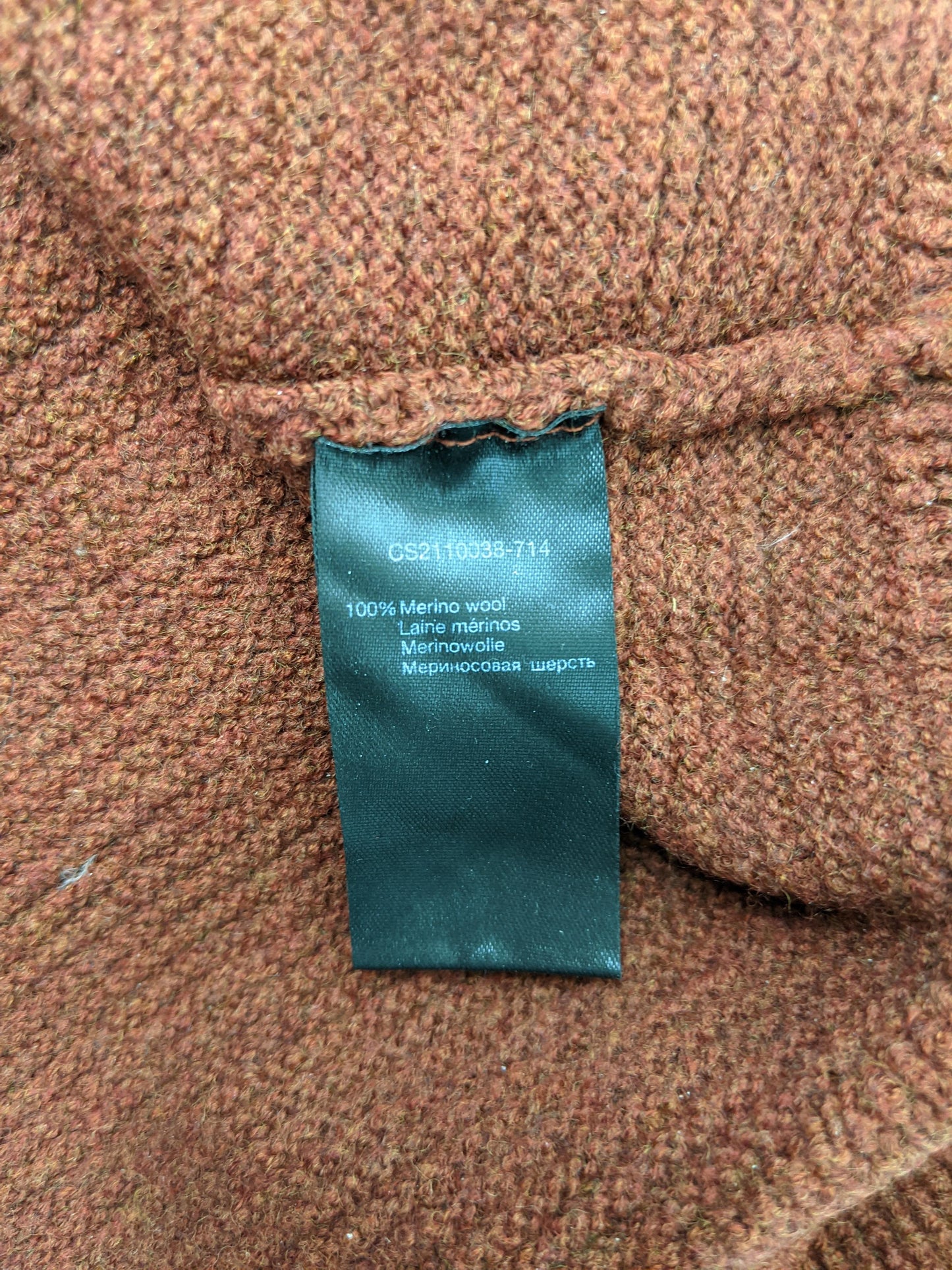 Close-up of size and material tag showing 100% Merino wool