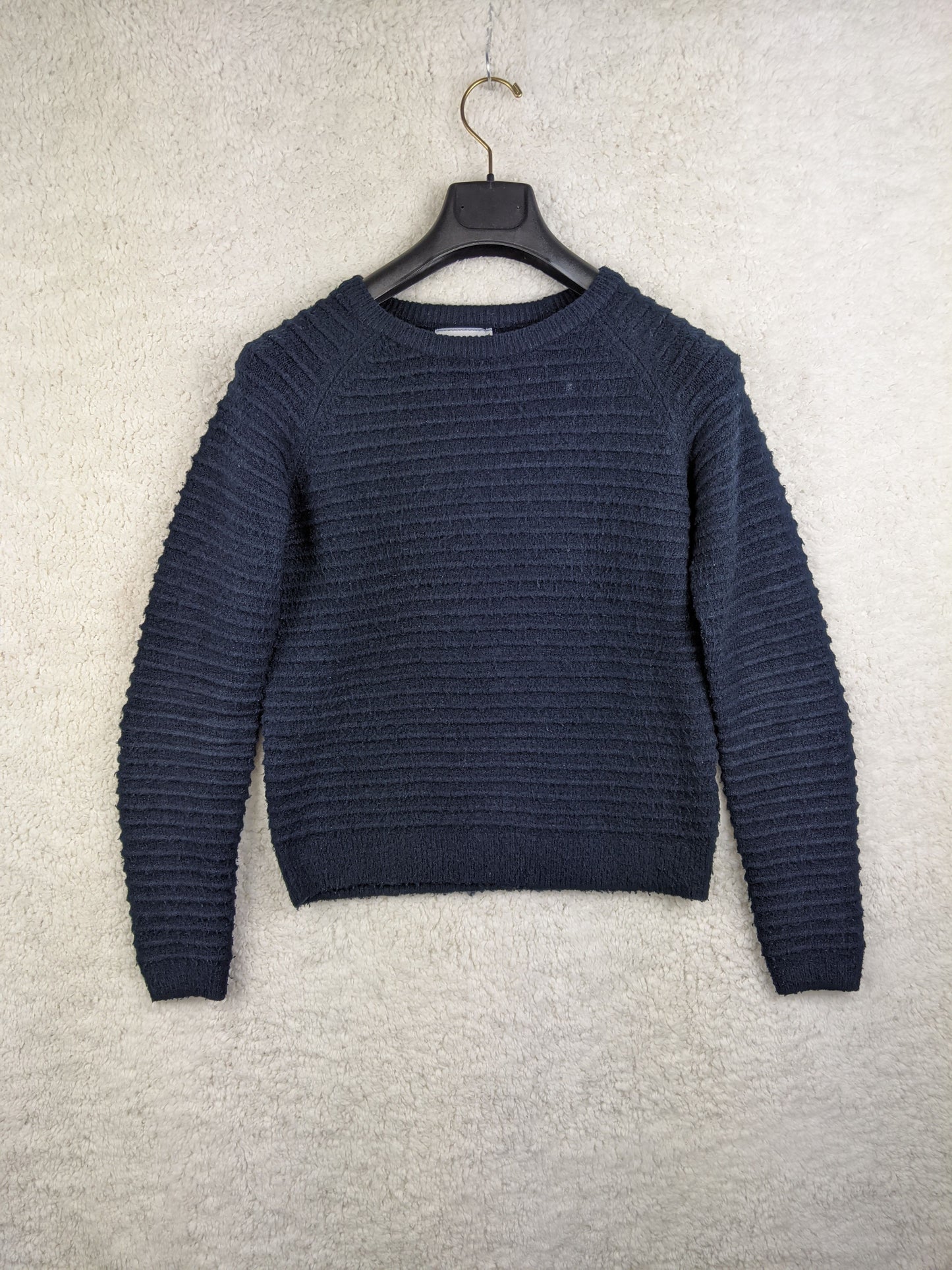 Navy textured sweater hanging on a hanger