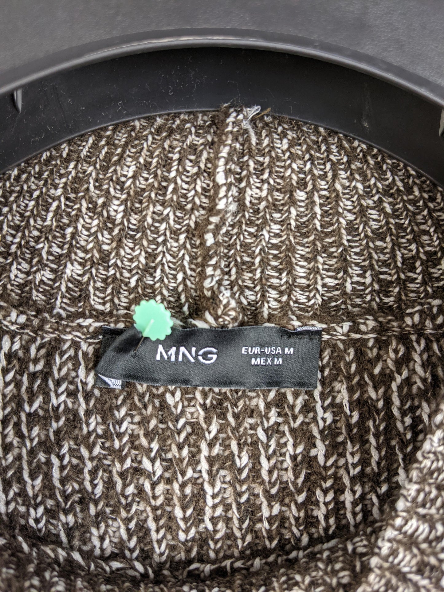 Close-up of MNG label on brown knit sweater