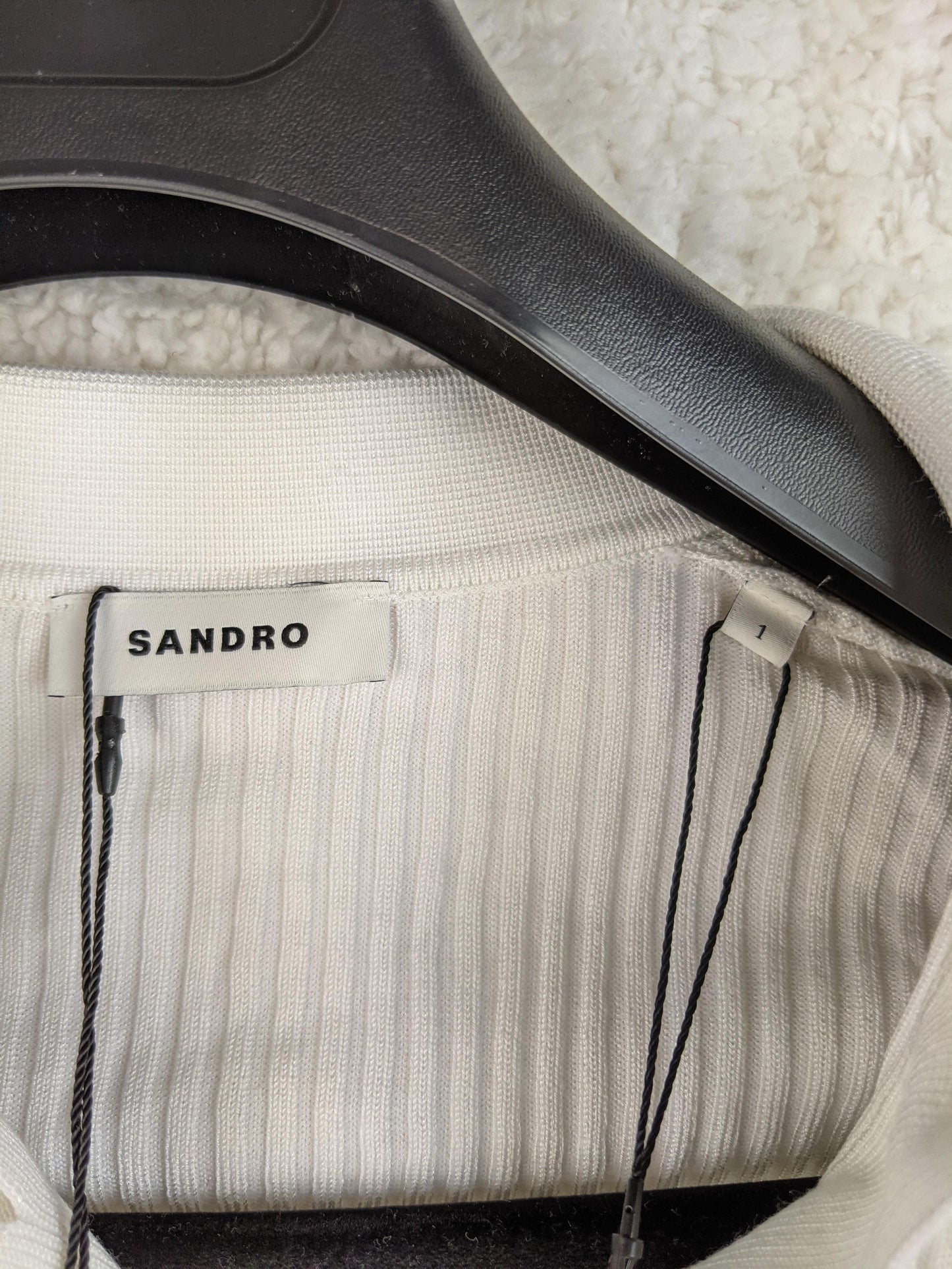 Close-up of Sandro brand label on white ribbed cardigan