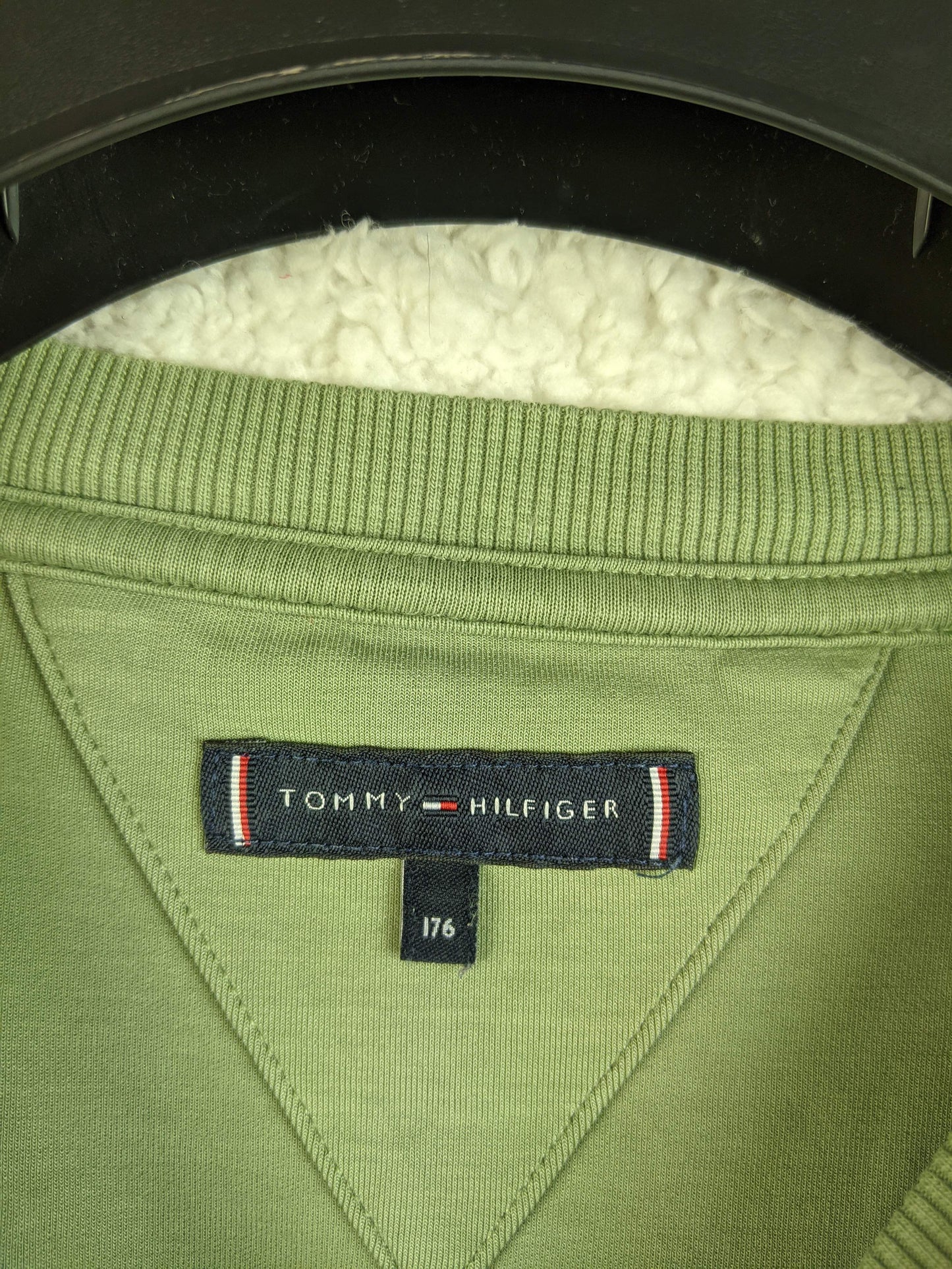 Close-up of Tommy Hilfiger label on green sweatshirt