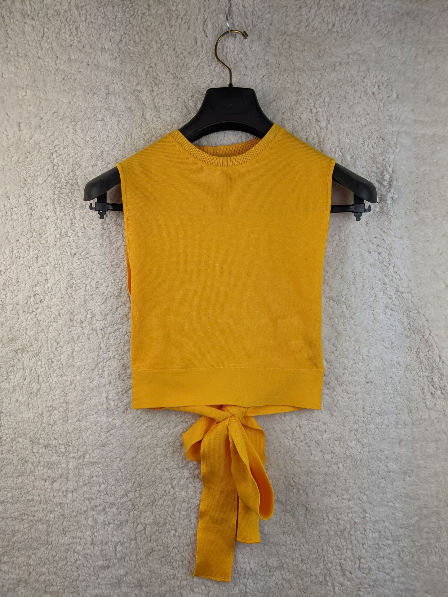 Yellow sleeveless top with tie-back on hanger - front view
