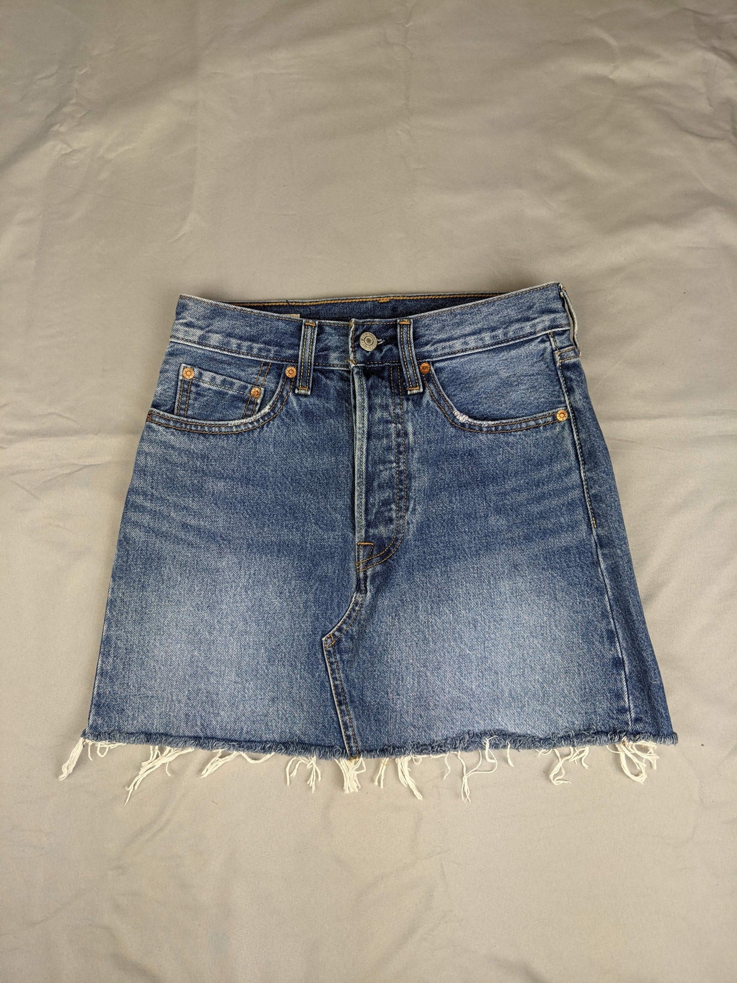 Front view of blue denim skirt with raw hem