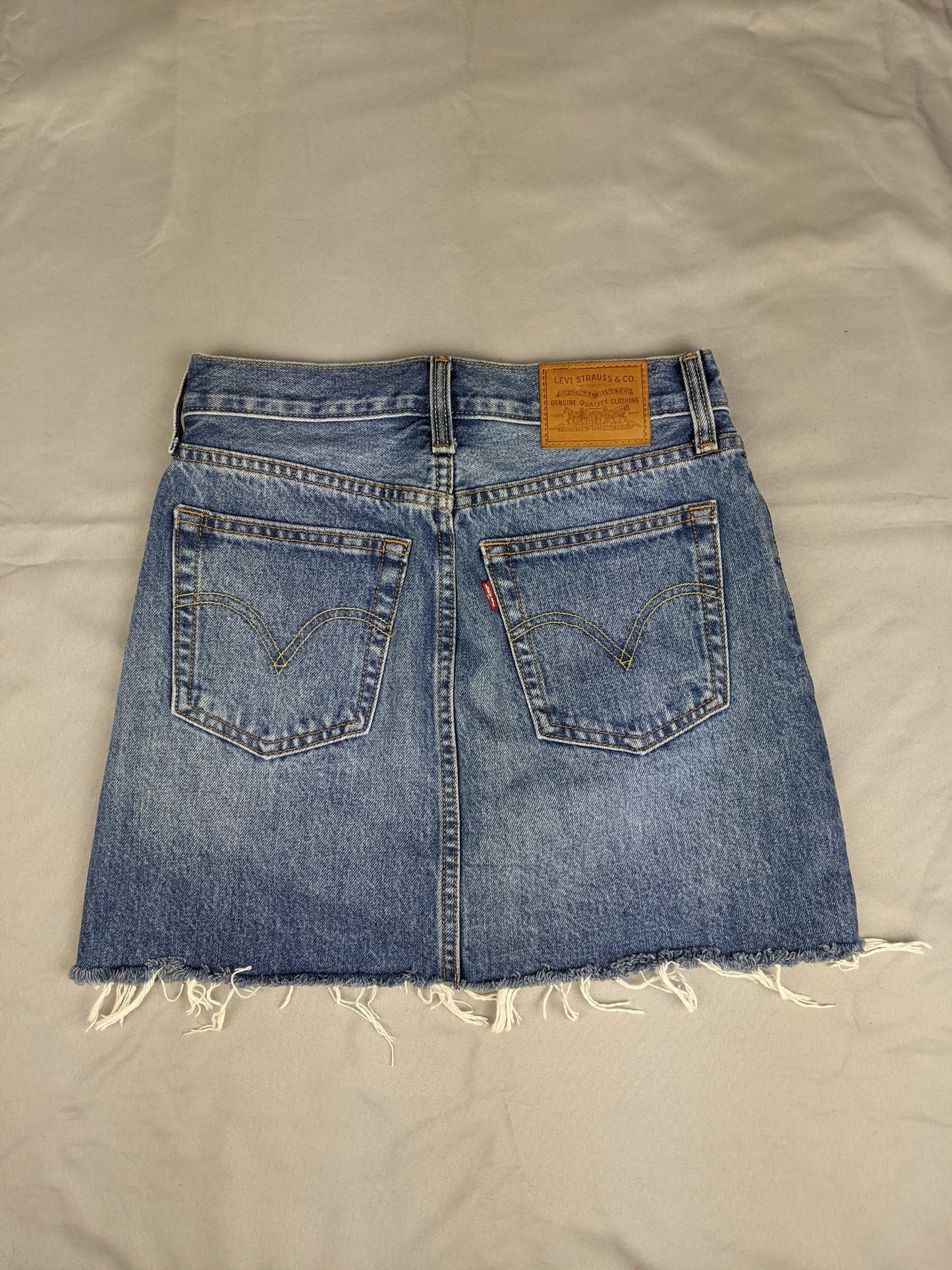 Back view of blue denim skirt with raw hem