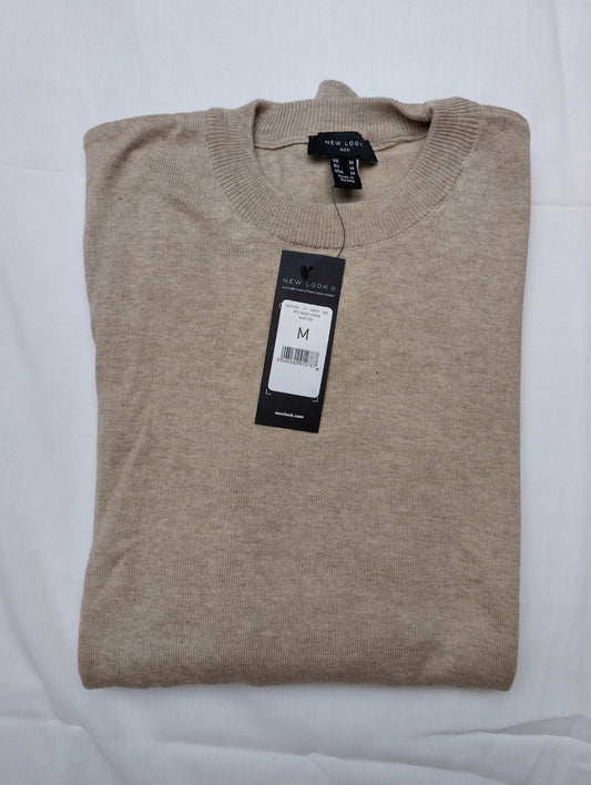 Folded beige sweater with tags