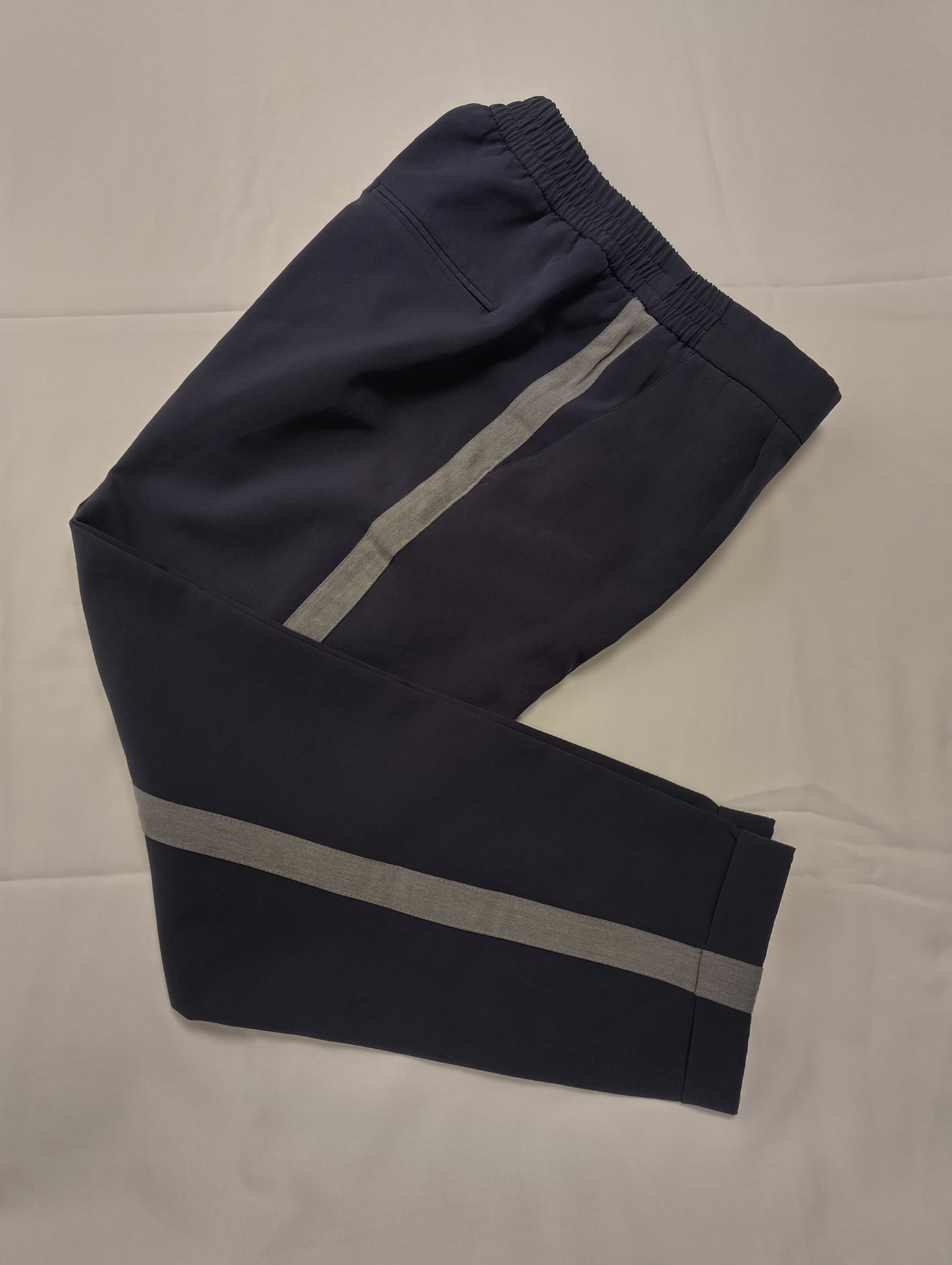 Folded navy pants showcasing side stripes