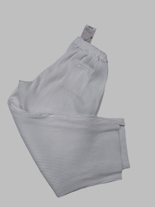 White pleated pants laid out on a neutral background