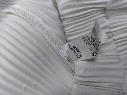Close-up of the inner label of the white pleated pants