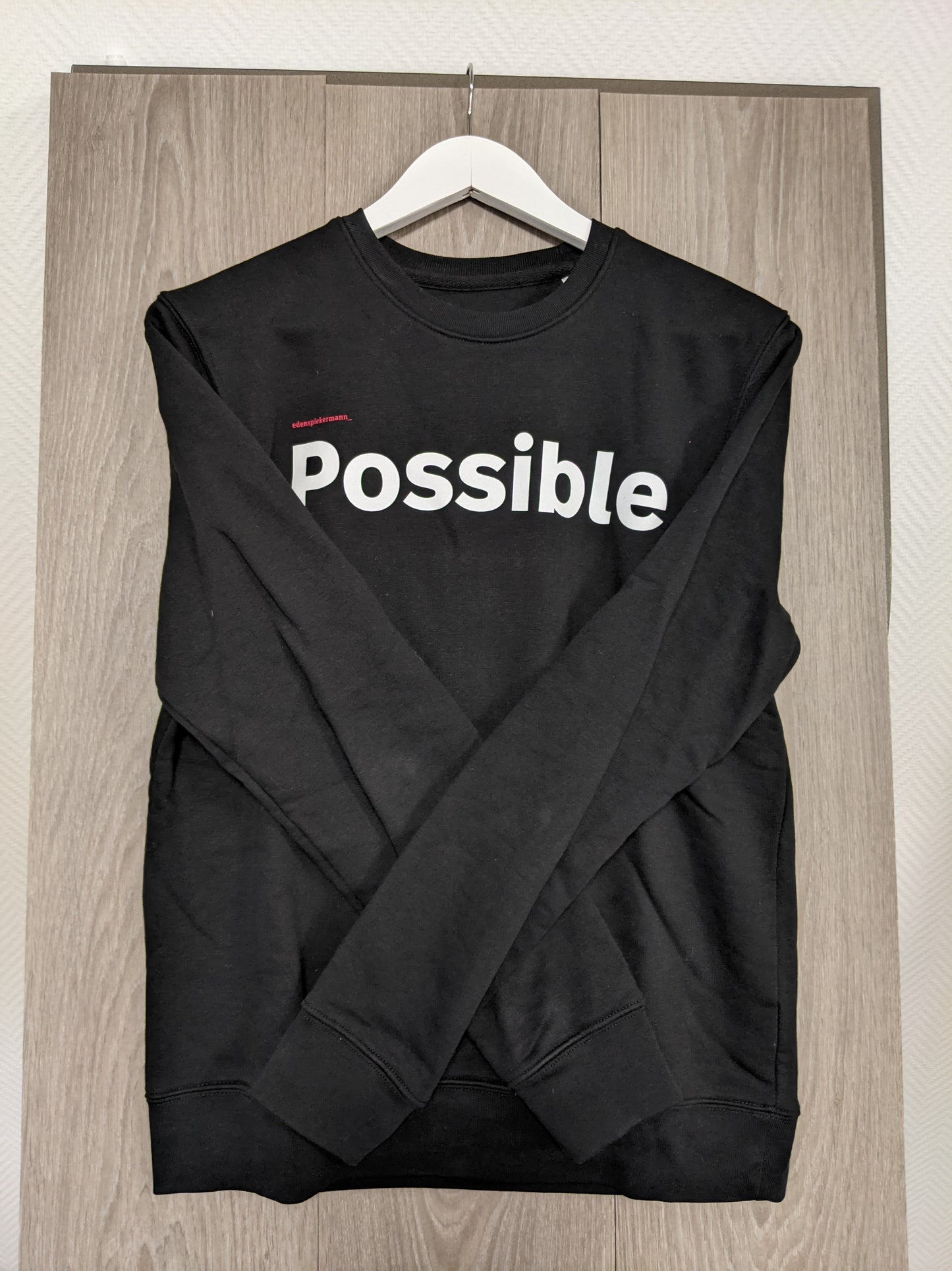 Side view of black sweatshirt with 'Possible' print