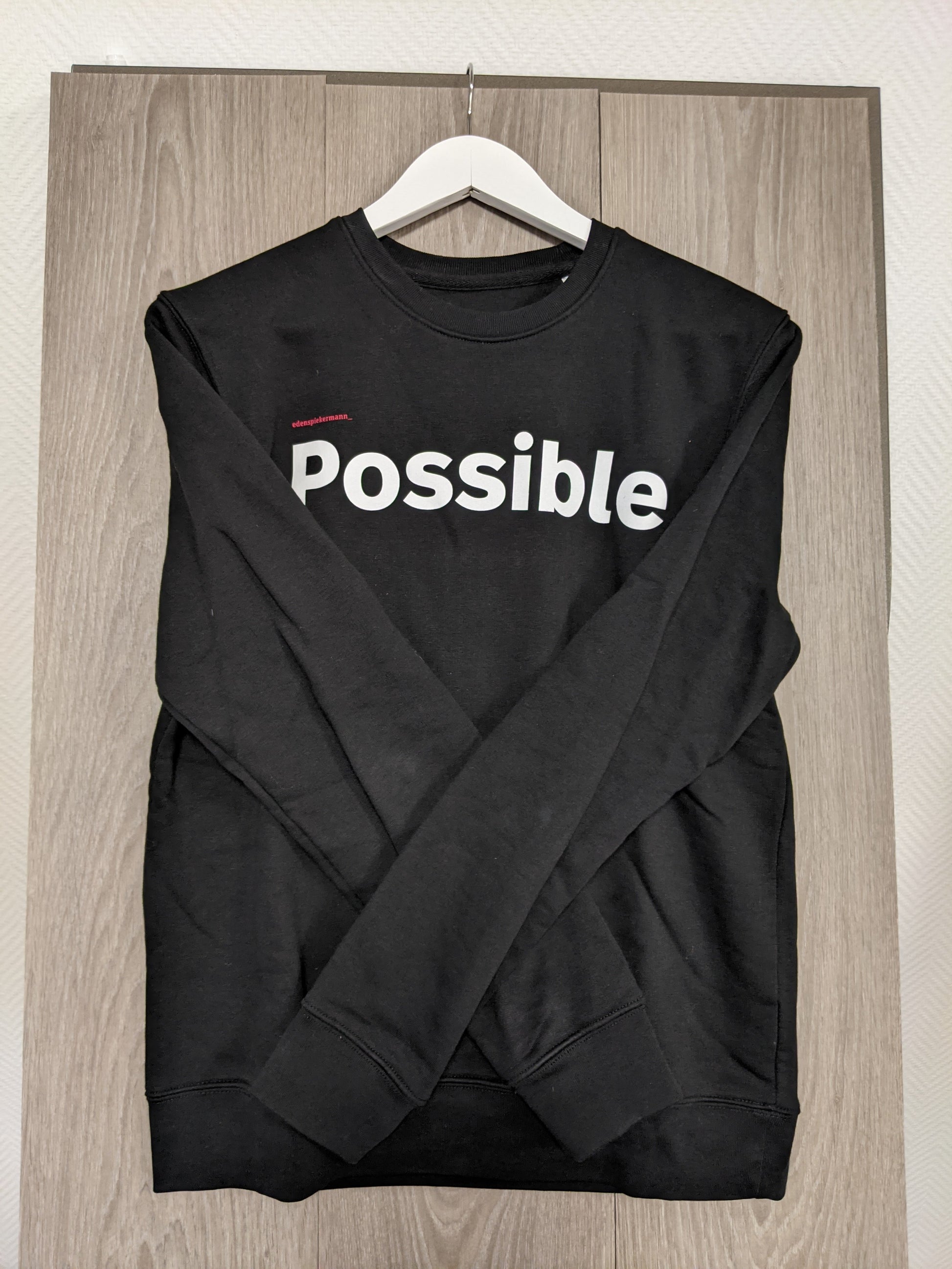 Side view of black sweatshirt with 'Possible' print