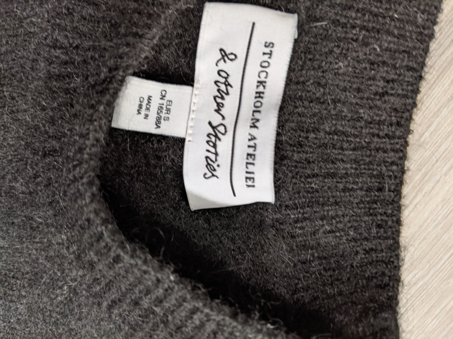 Tag inside the black striped sweater noting brand and size