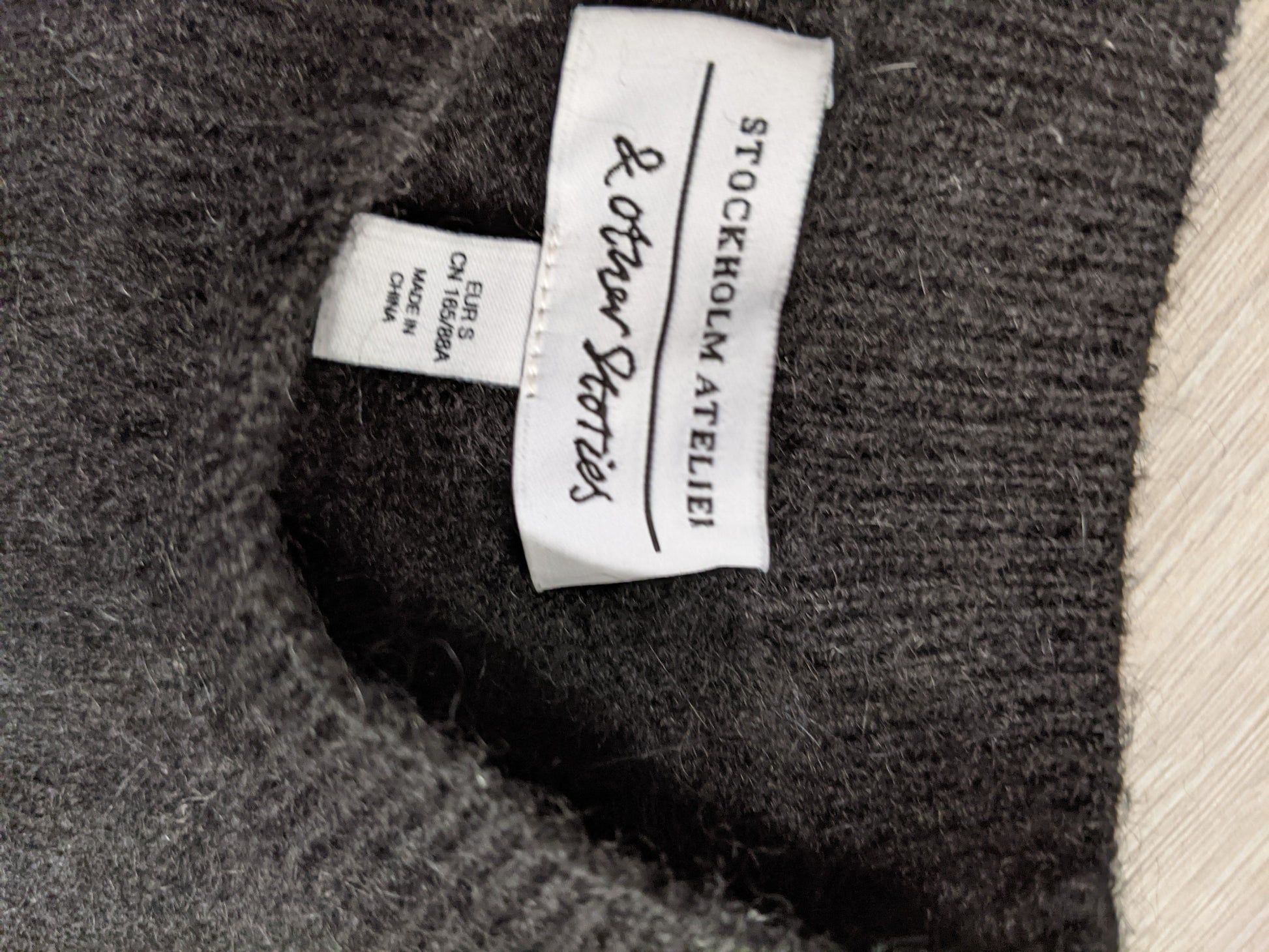 Tag inside the black striped sweater noting brand and size