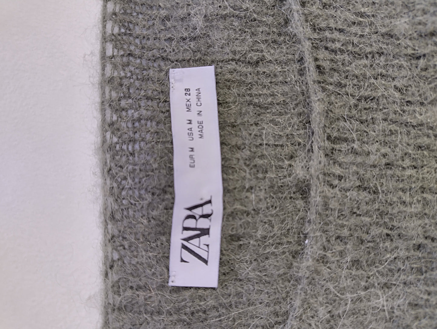 Zara label on olive green sweater