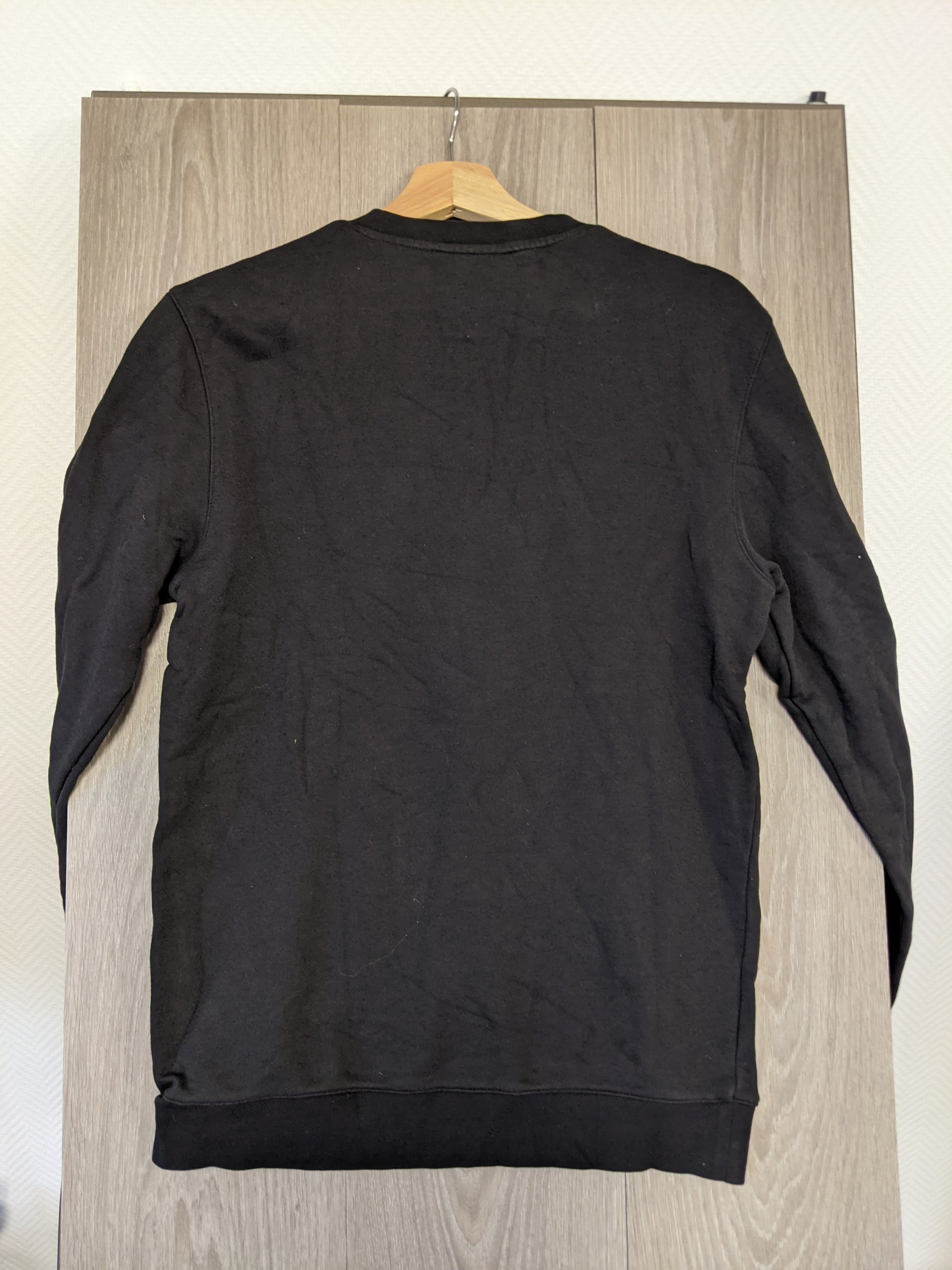 Back view of black sweater hanging