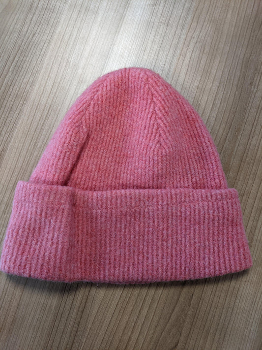 Pink knit beanie on wooden surface