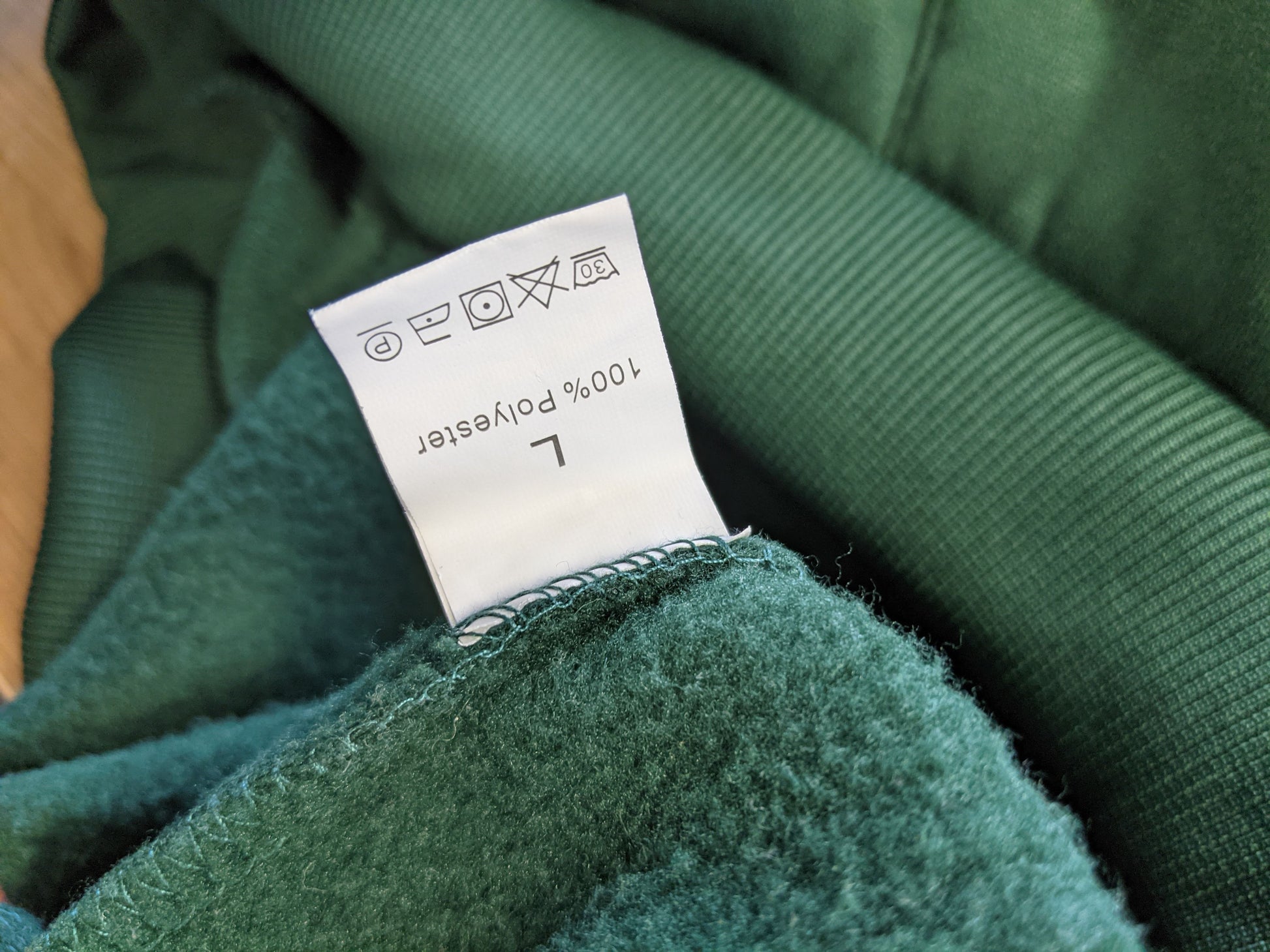 Close-up of label on green hoodie showing size and material