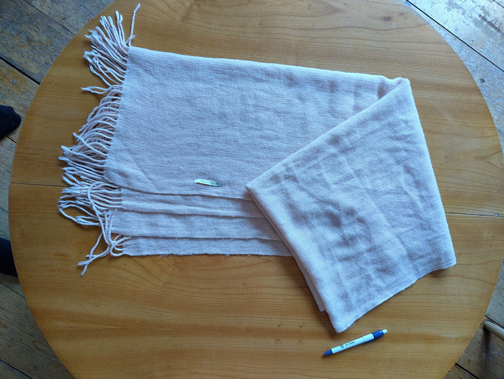 Soft lightweight pink scarf spread out on a wooden table