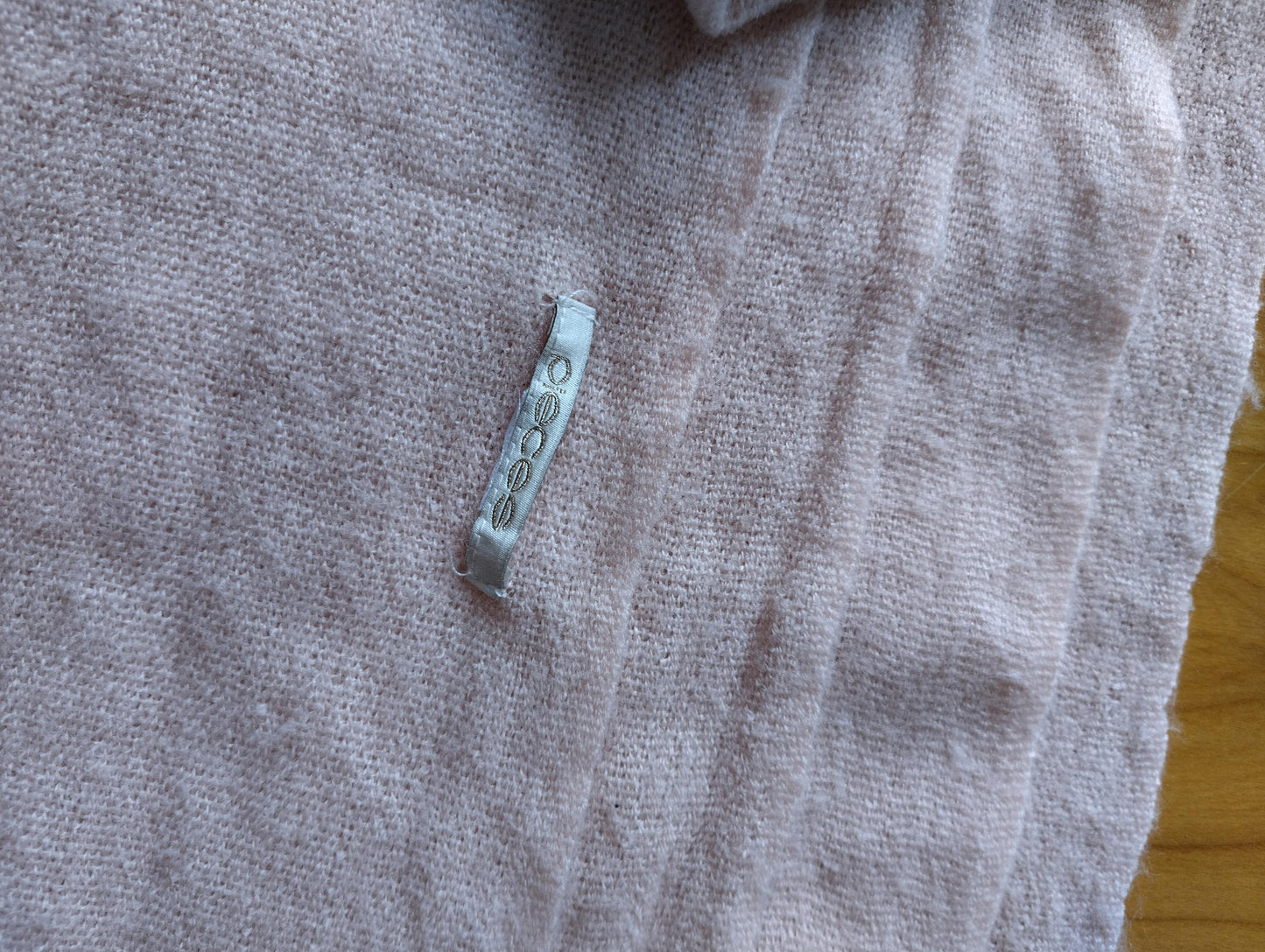 Close-up showing the texture and tag of the pink scarf