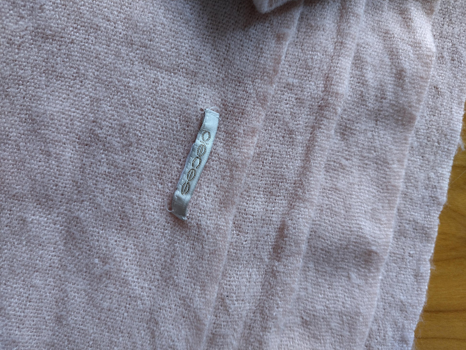 Close-up showing the texture and tag of the pink scarf
