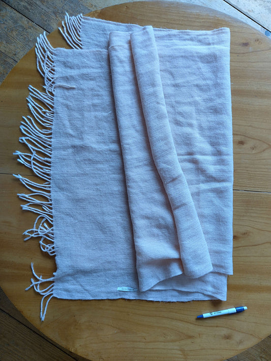 Folded pink scarf on a wooden table with pen for size reference