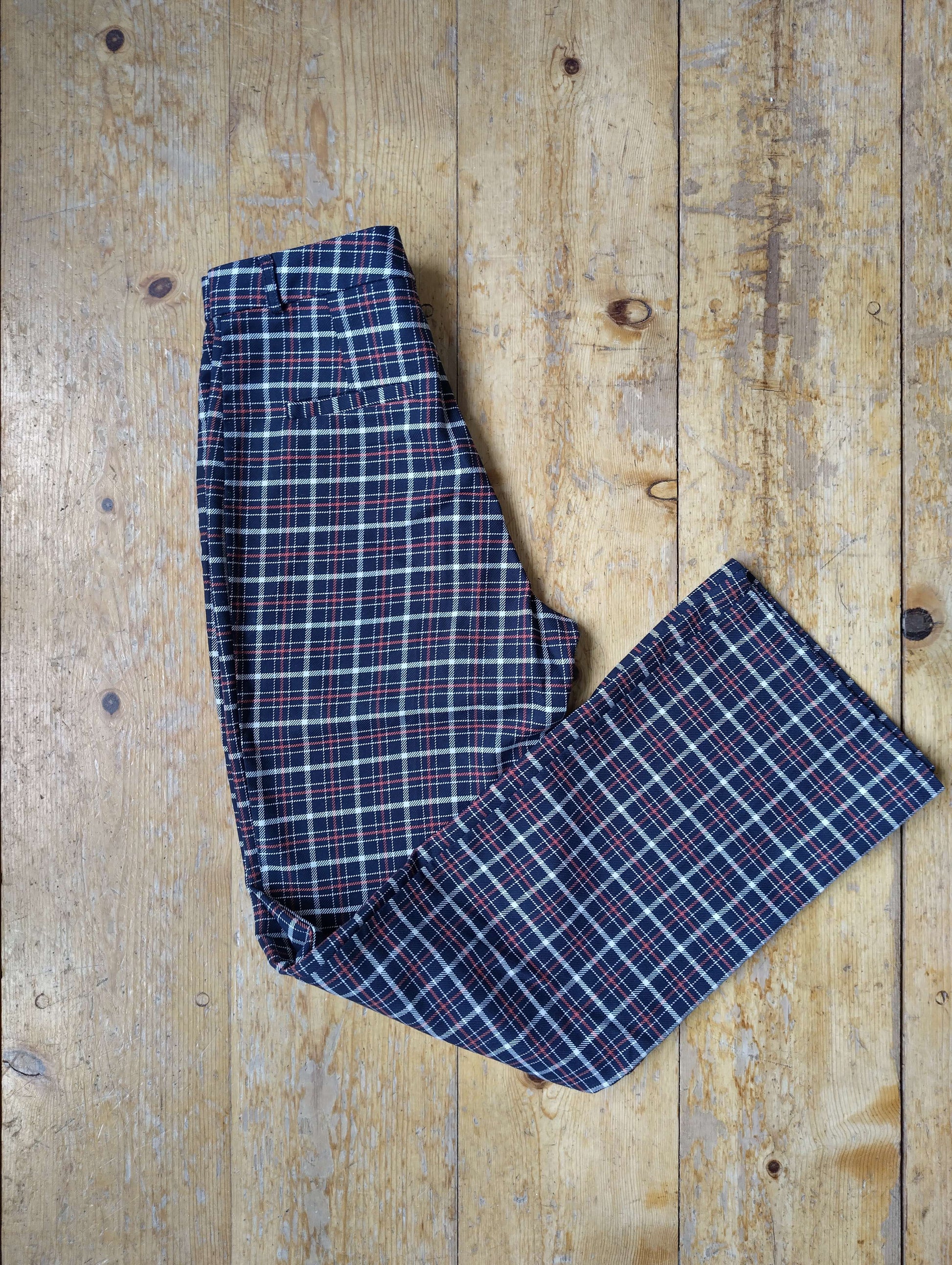 Folded red plaid pants on wooden floor