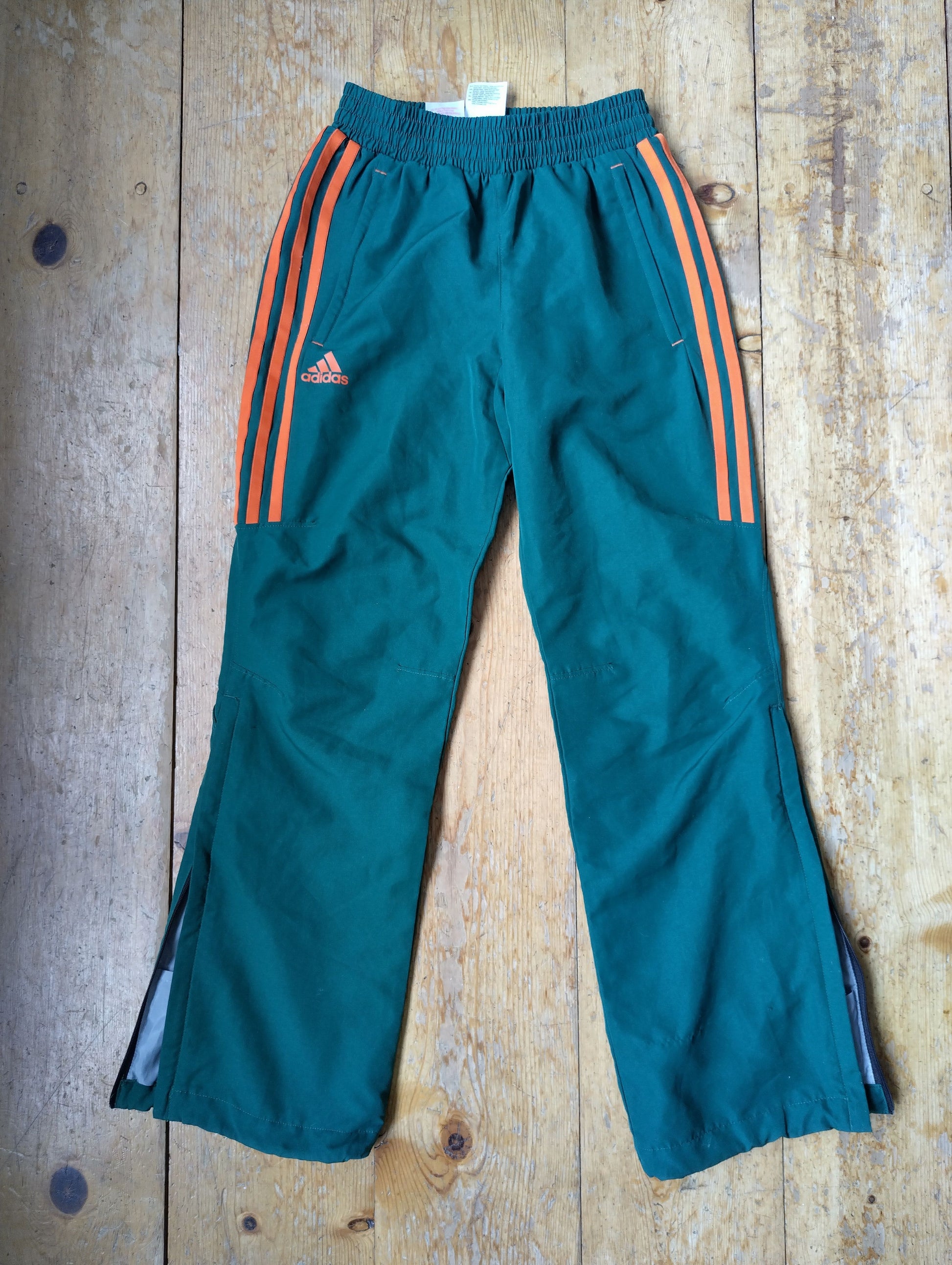 Green Adidas track pants with orange stripes on the front side