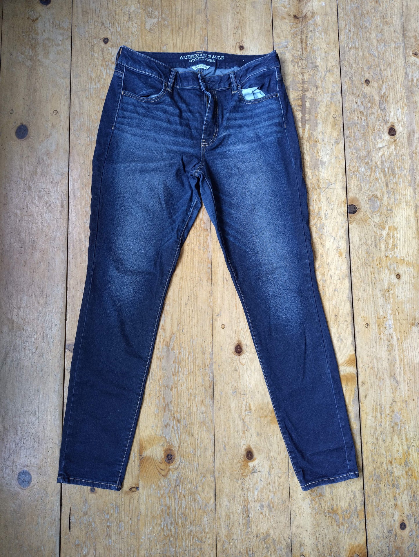 Front view of dark blue jeans on wooden floor