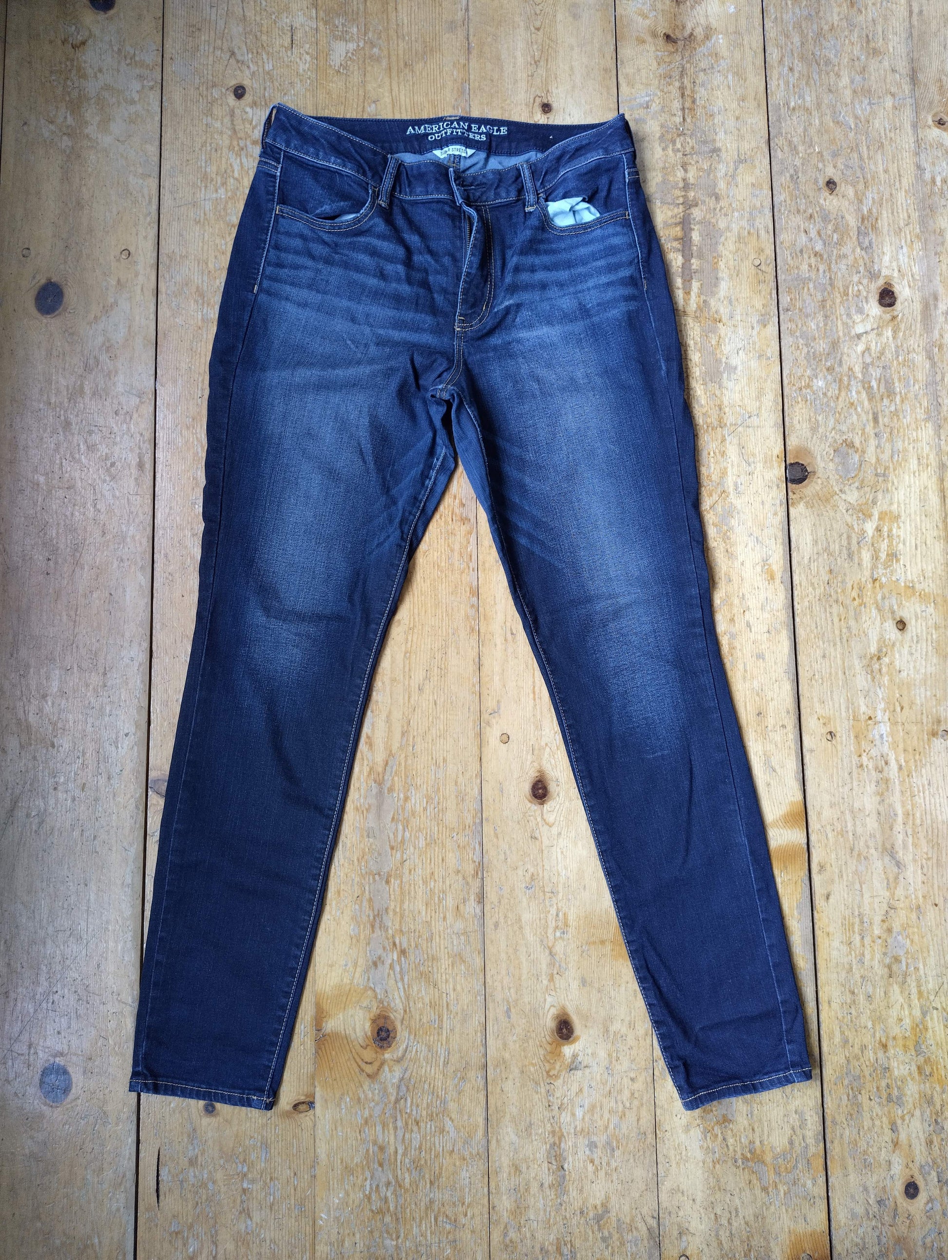 Front view of dark blue jeans on wooden floor