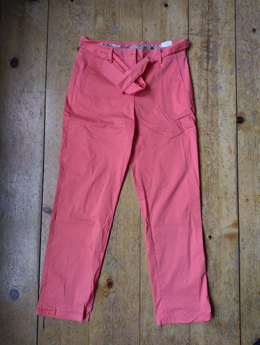 Pink belted trousers laid flat on a wooden surface