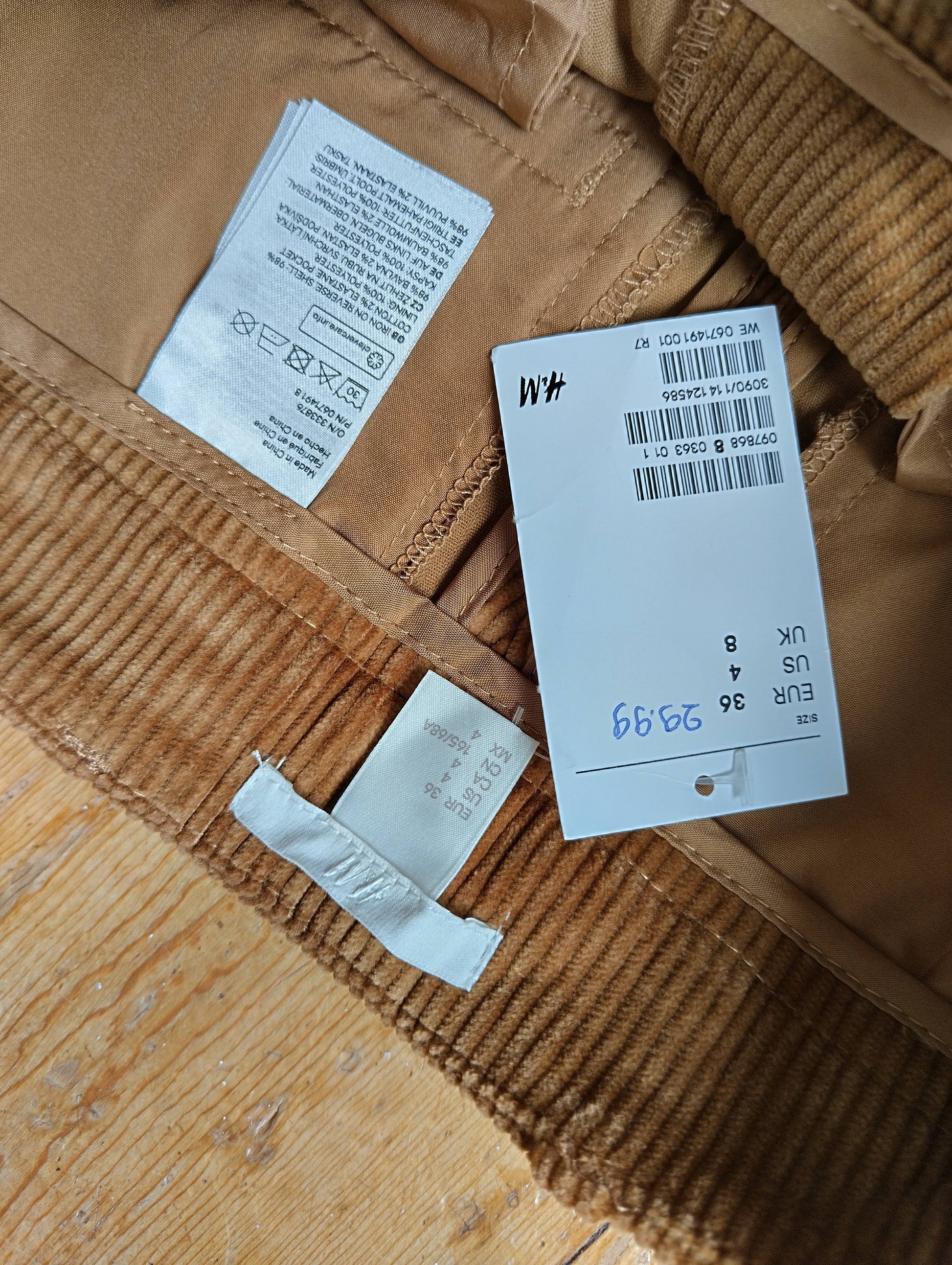 Close-up of tags on tan corduroy trousers