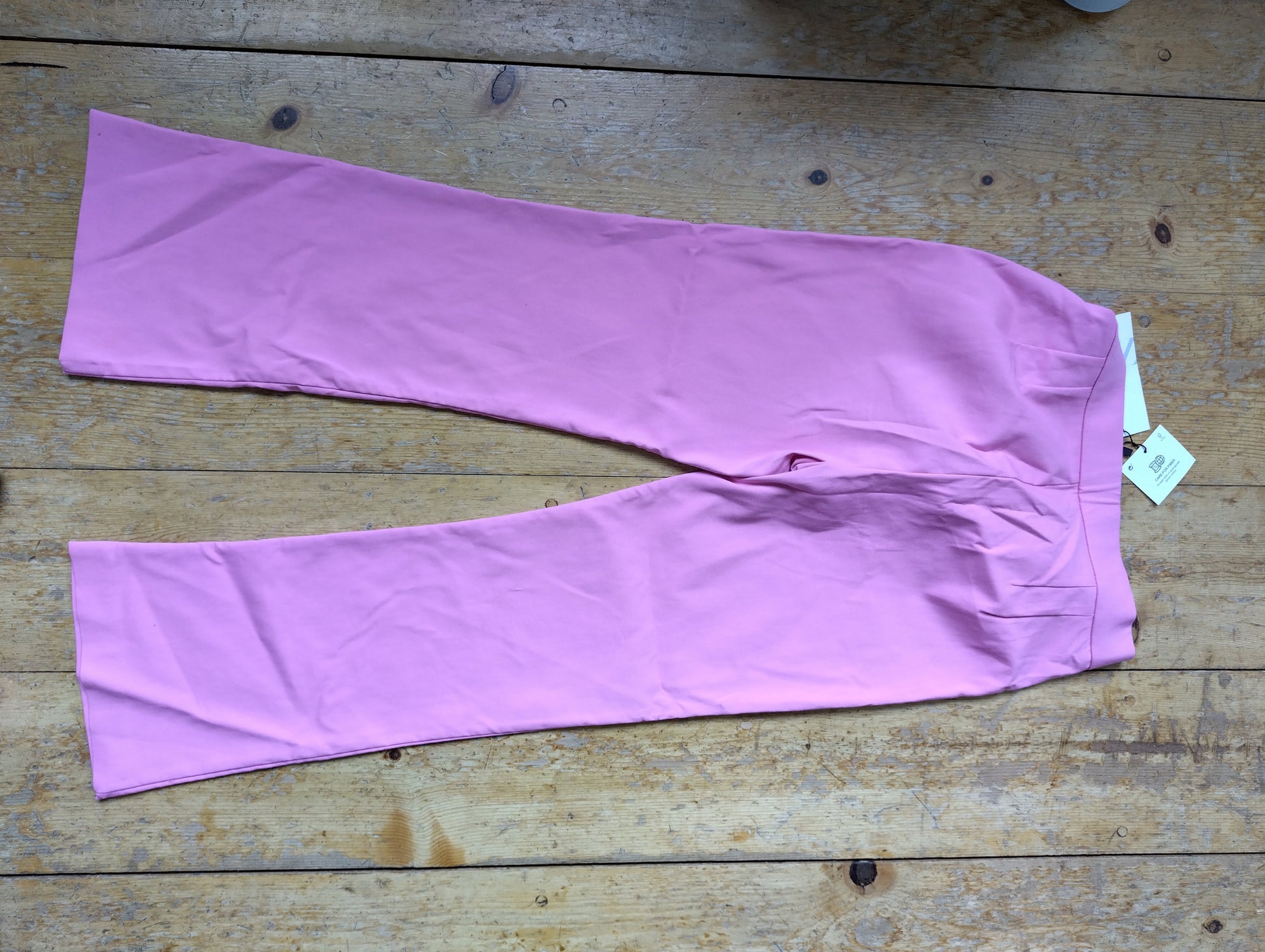 Side view of pink flare pants on a wooden surface