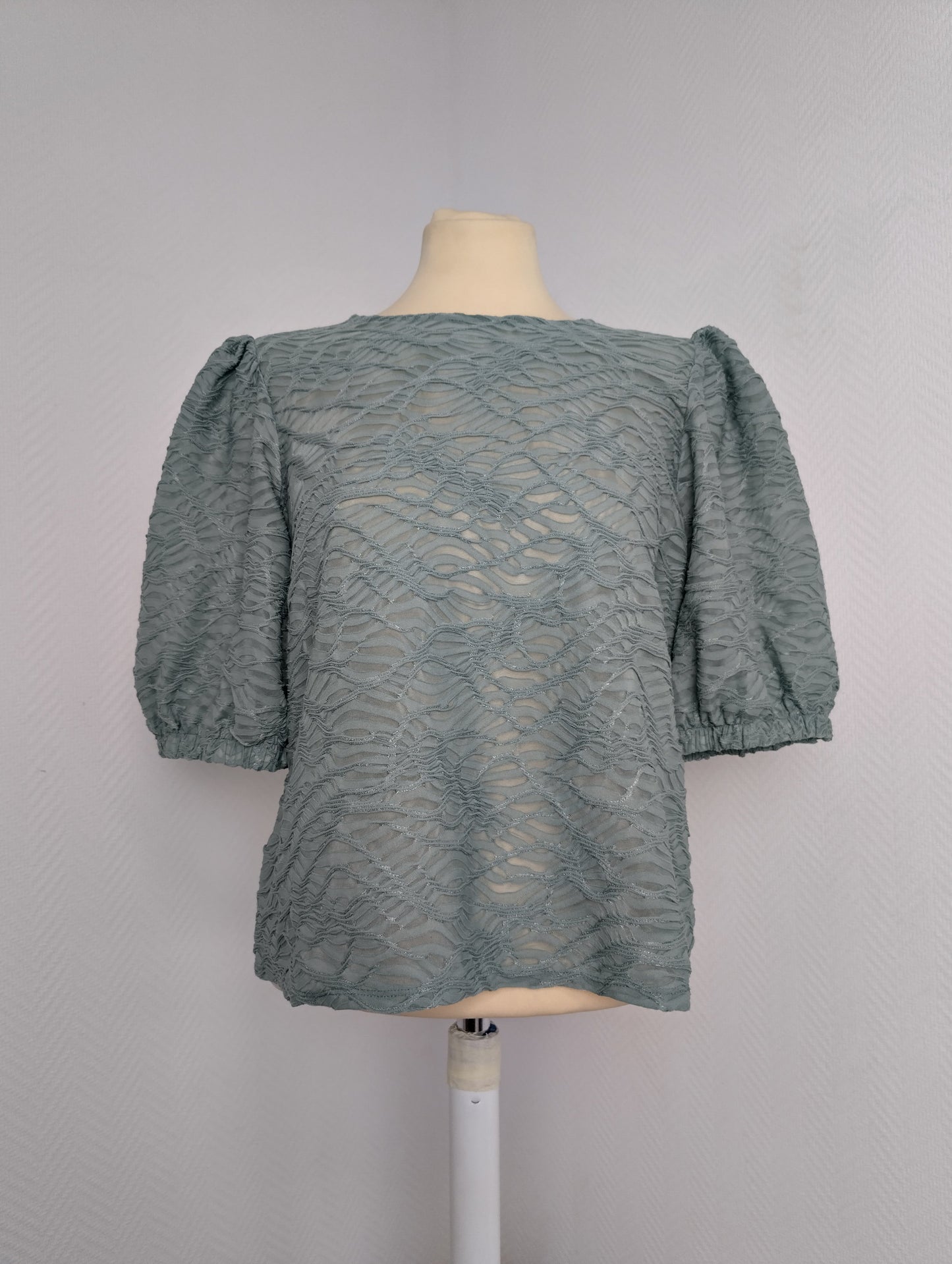 Front view of sage green lace blouse on mannequin