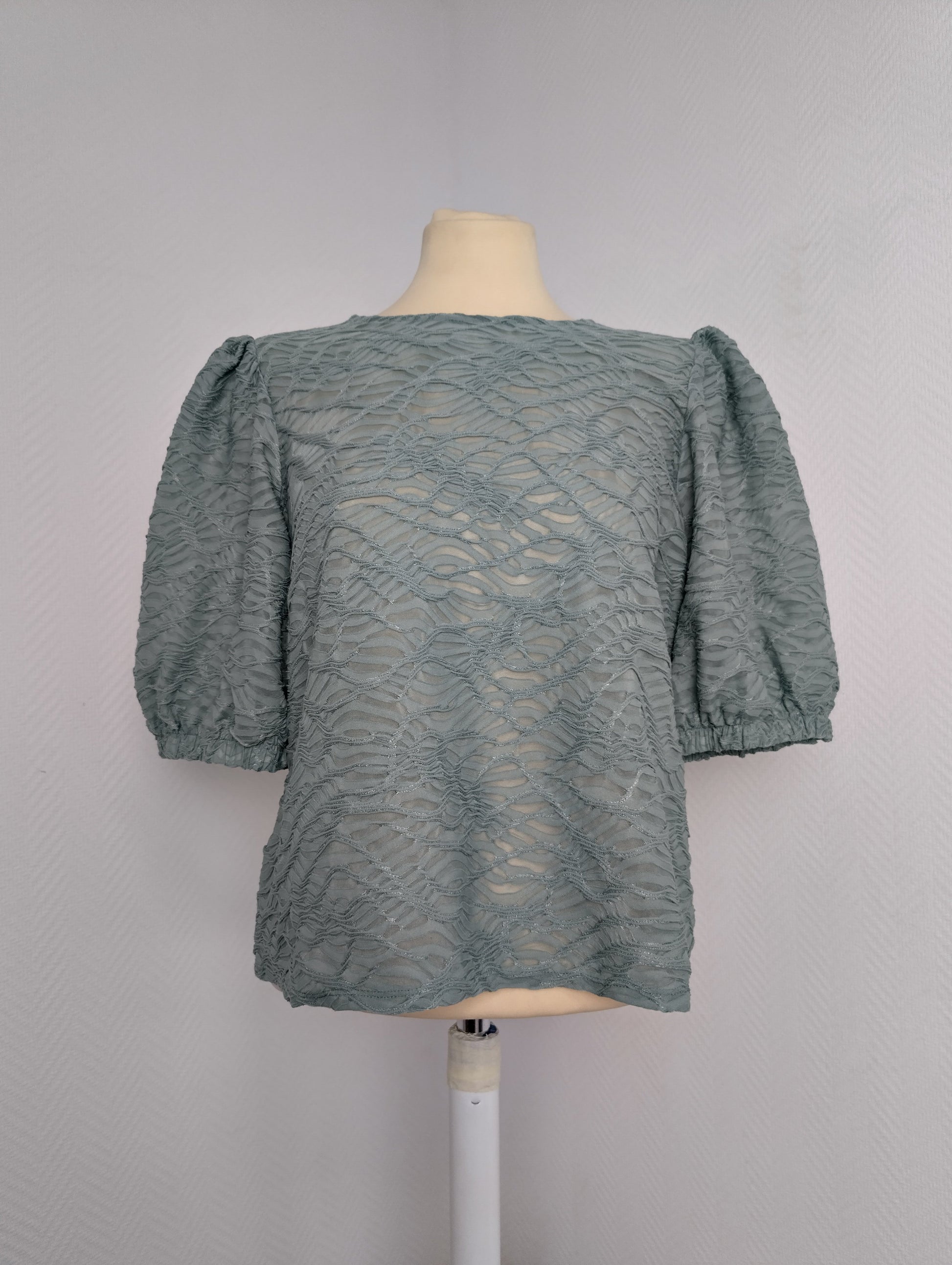 Front view of sage green lace blouse on mannequin
