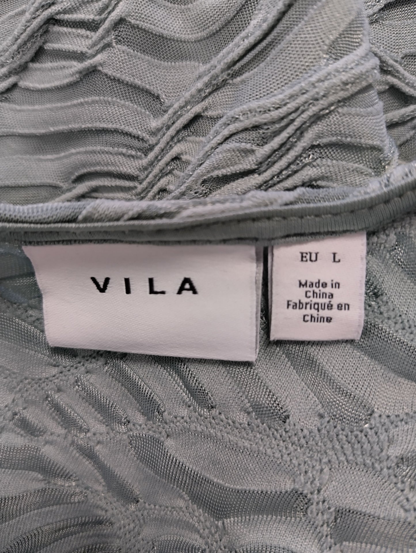 Close-up of Vila brand label on sage green blouse