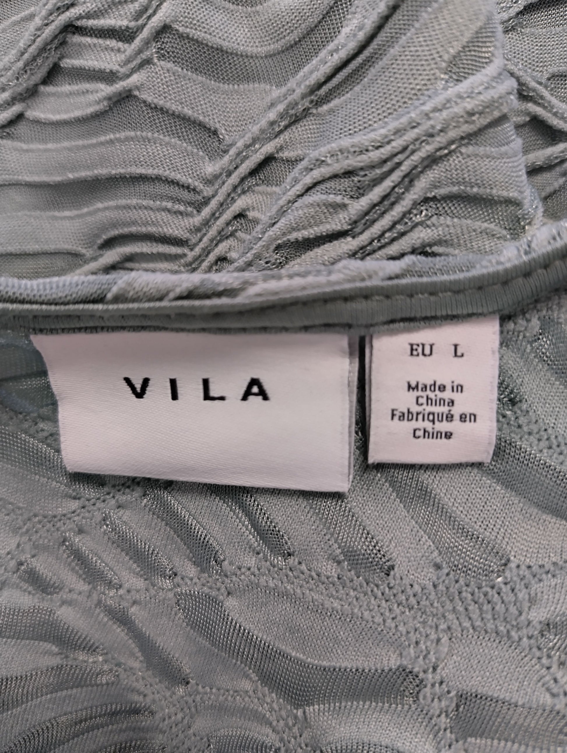 Close-up of Vila brand label on sage green blouse
